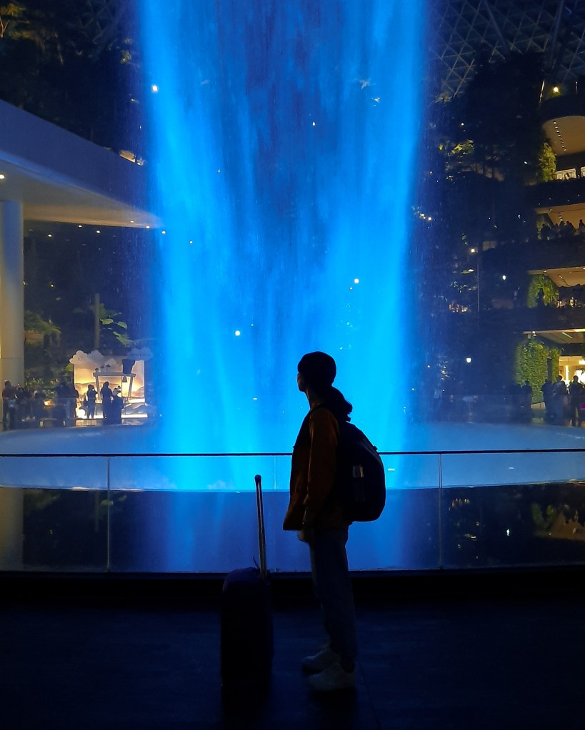 Girl in silhouette standing in front of Changi Airport's Rain Vortex