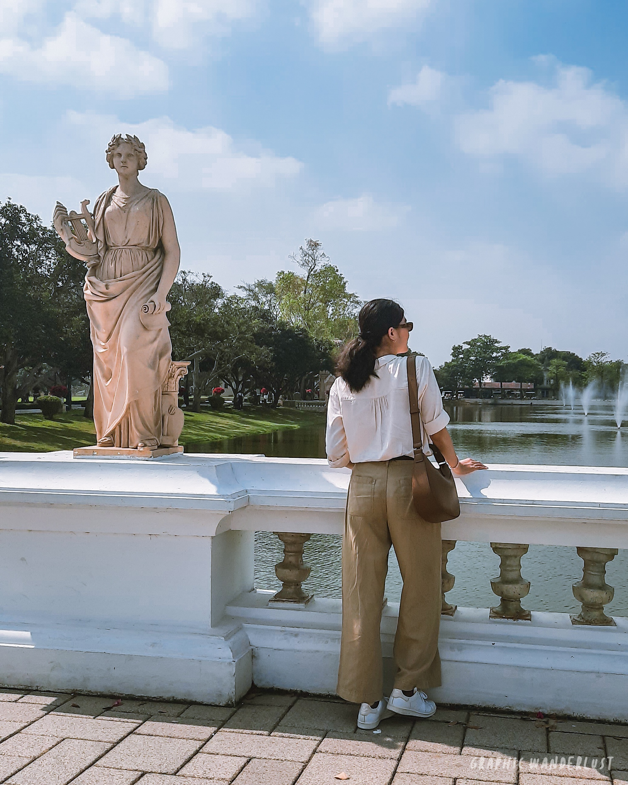 Girl standing beside a Greek-inspired sculpture on a bridge