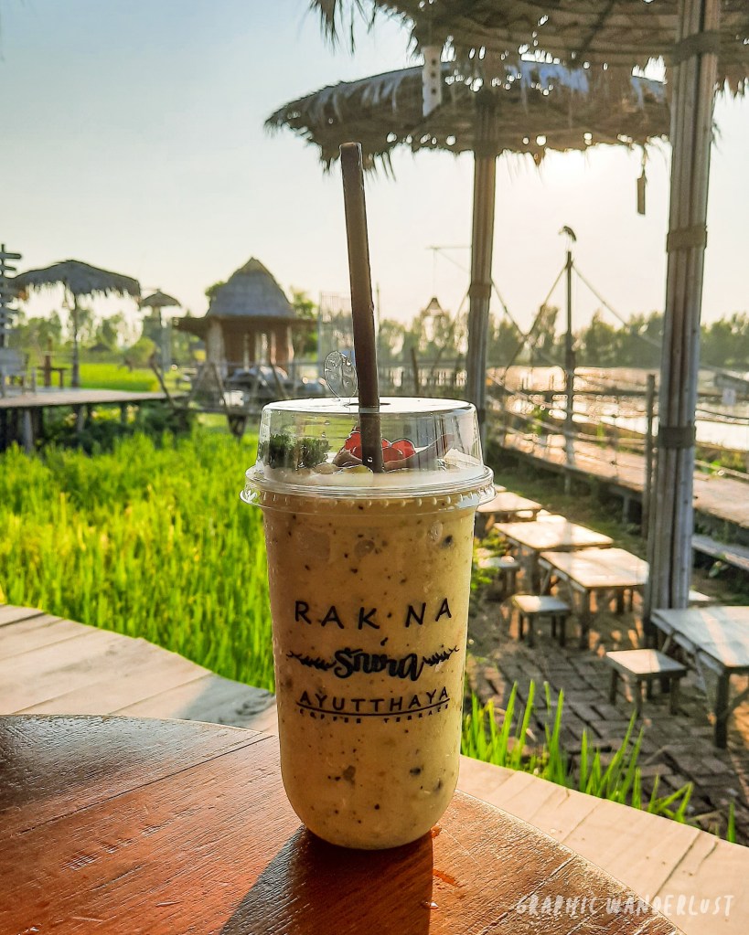 A refreshing avocado and passionfruit smoothie served at Rak Na Café in Ayutthaya, with rice fields in the background.