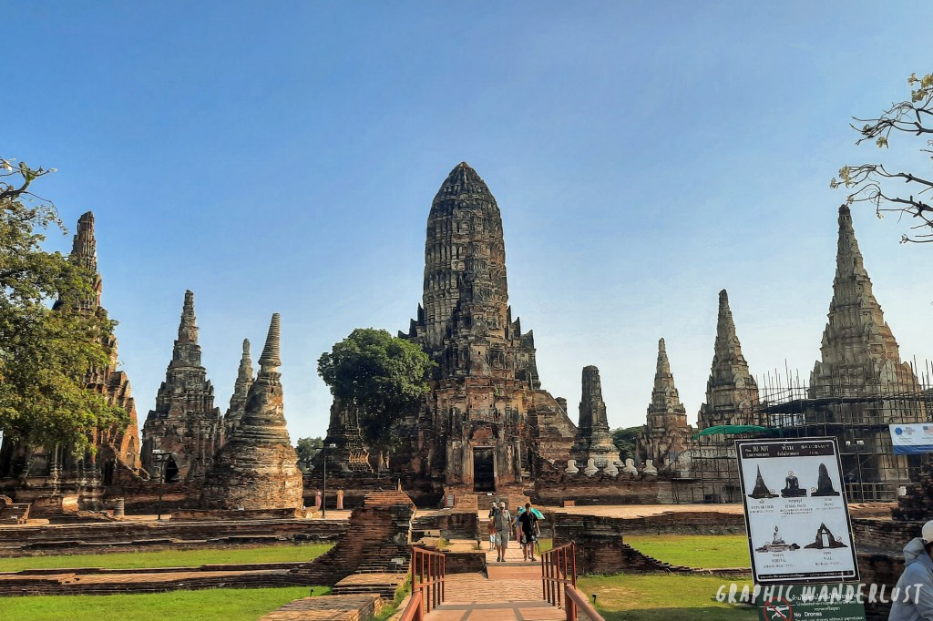 View of the temple ruins at Wat Mahathat in Ayutthaya, featuring ancient prangs and a clear blue sky.
