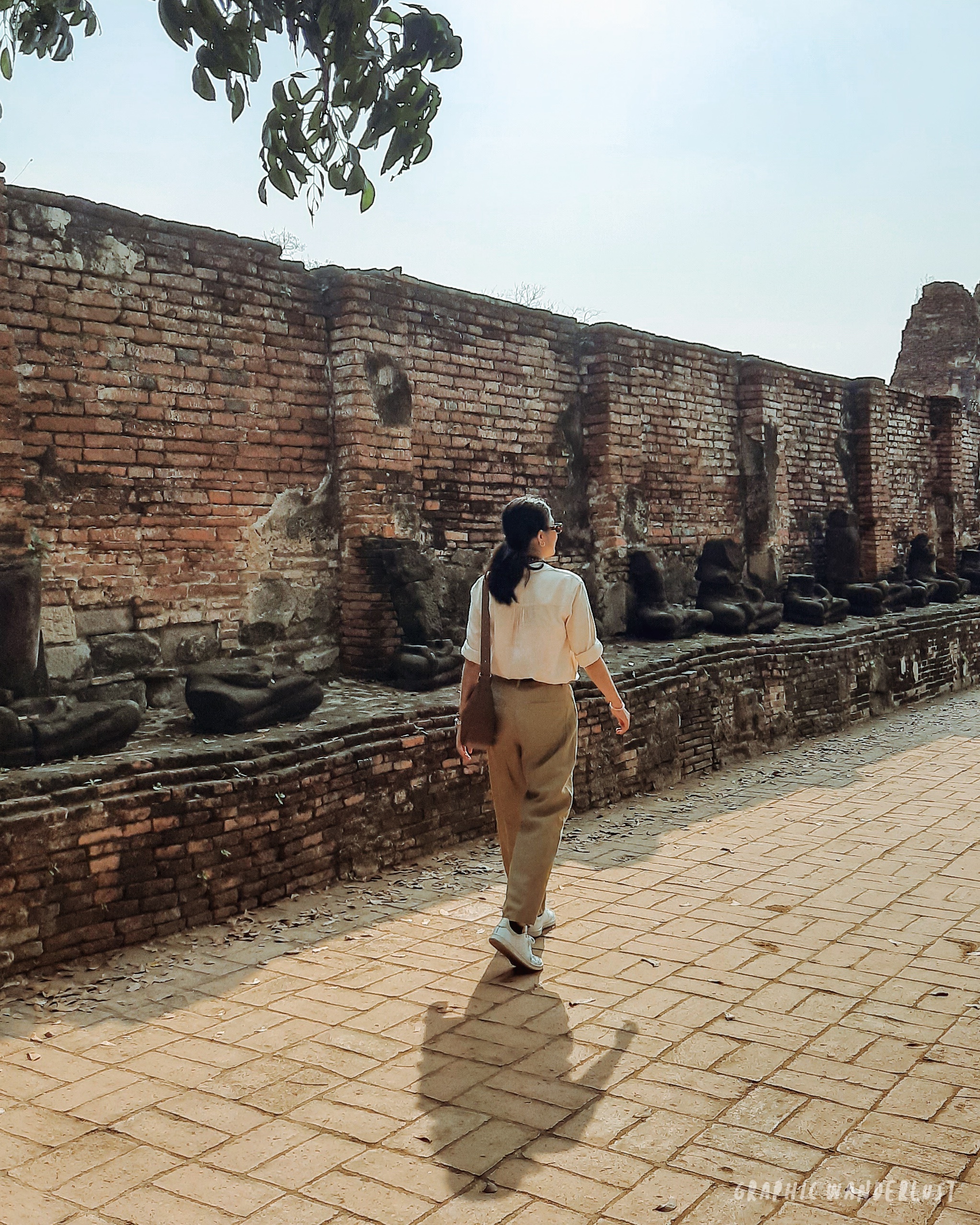 Girl walking along the gallery of headless Buddha images in Wat Mahathat