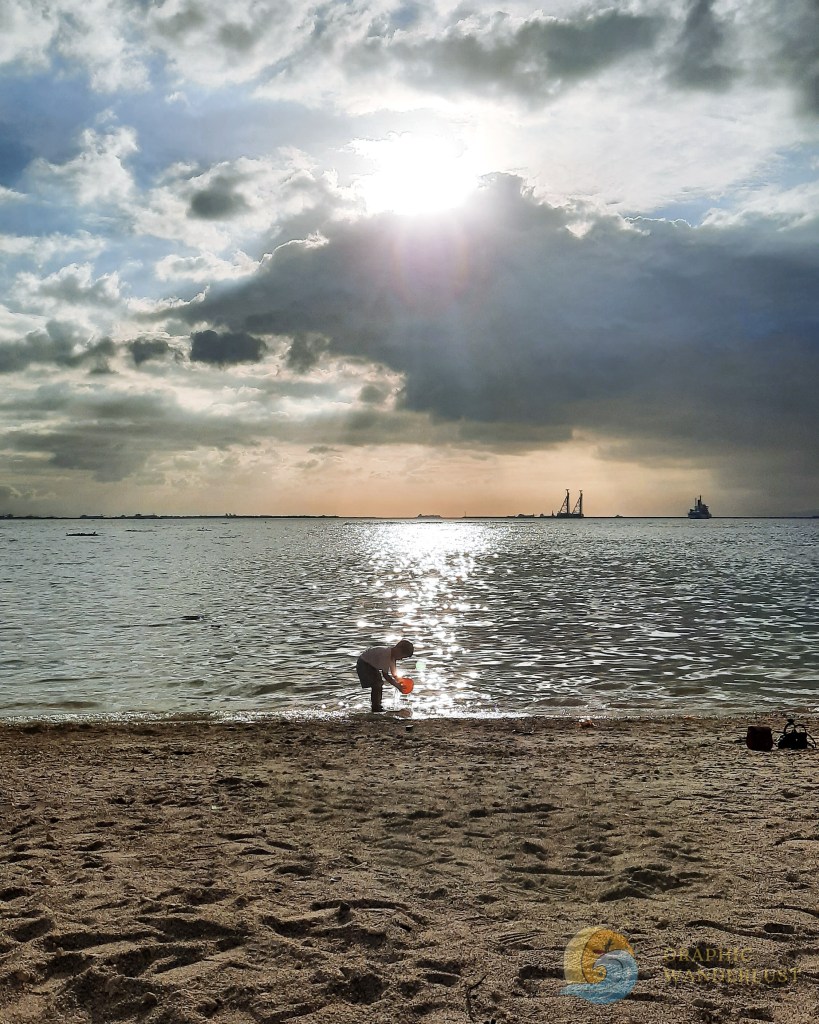 A little boy playing sand in front of Manila Bay in Dolomite Beach