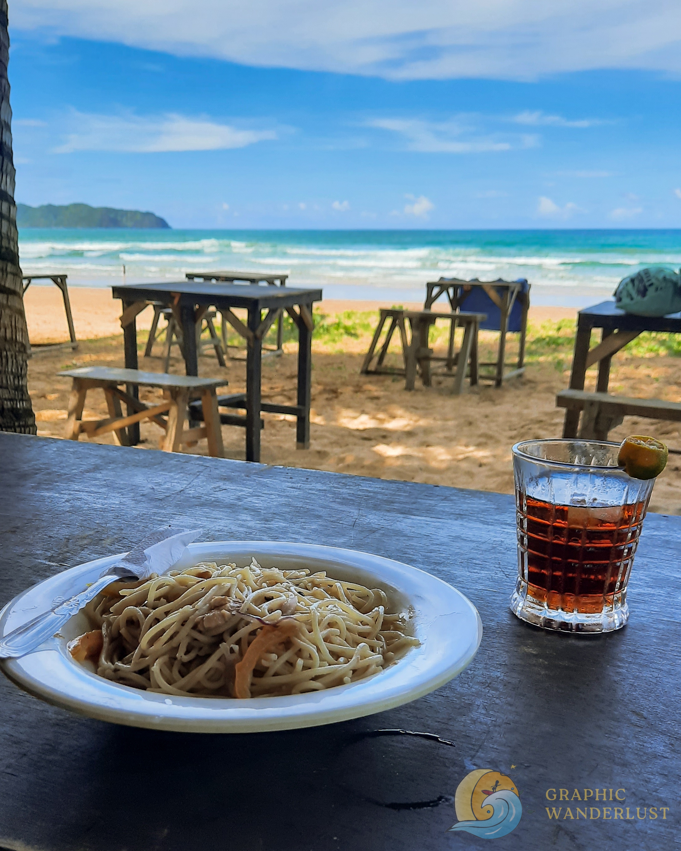 Serving of pasta and cocktail with a background of a beach