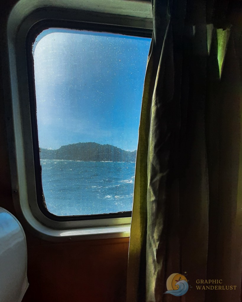 Window view from a ferry featuring a nearby island