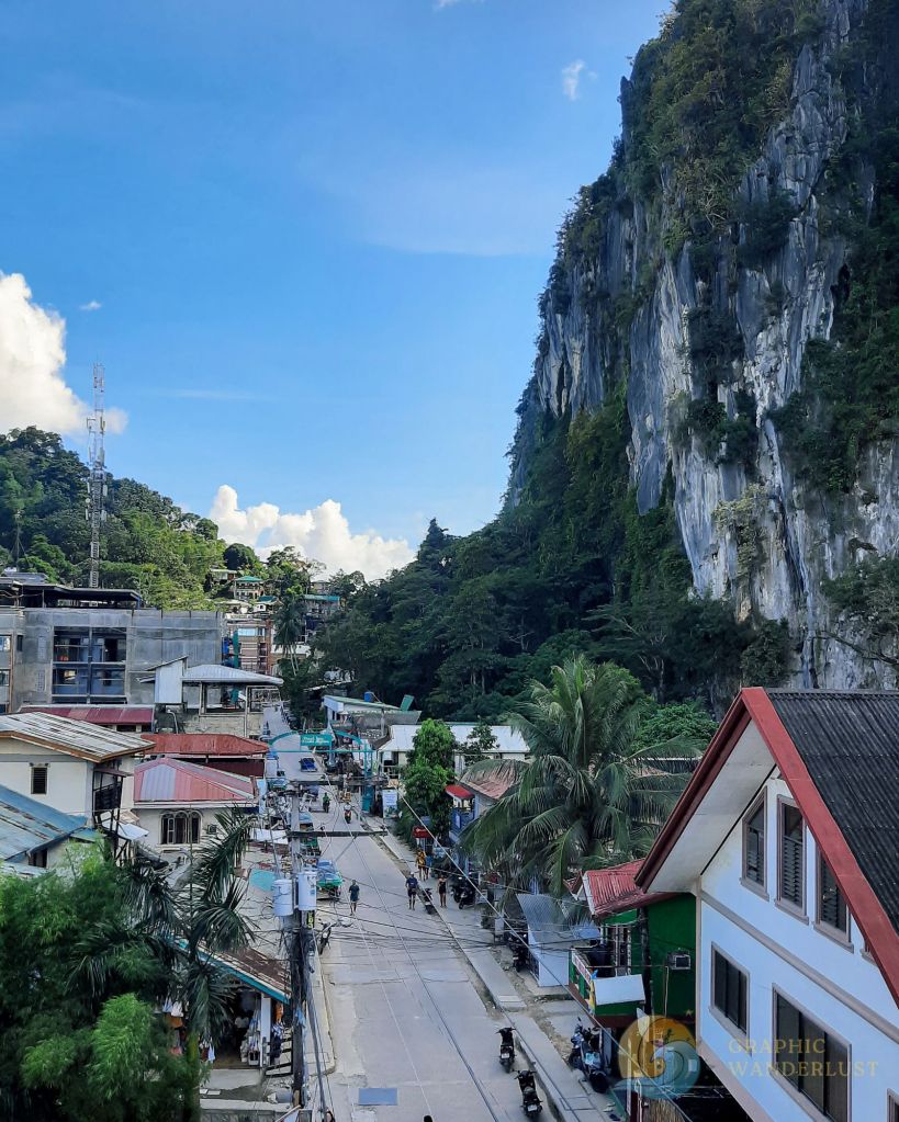 Rural town towered over by a big limestone cliff