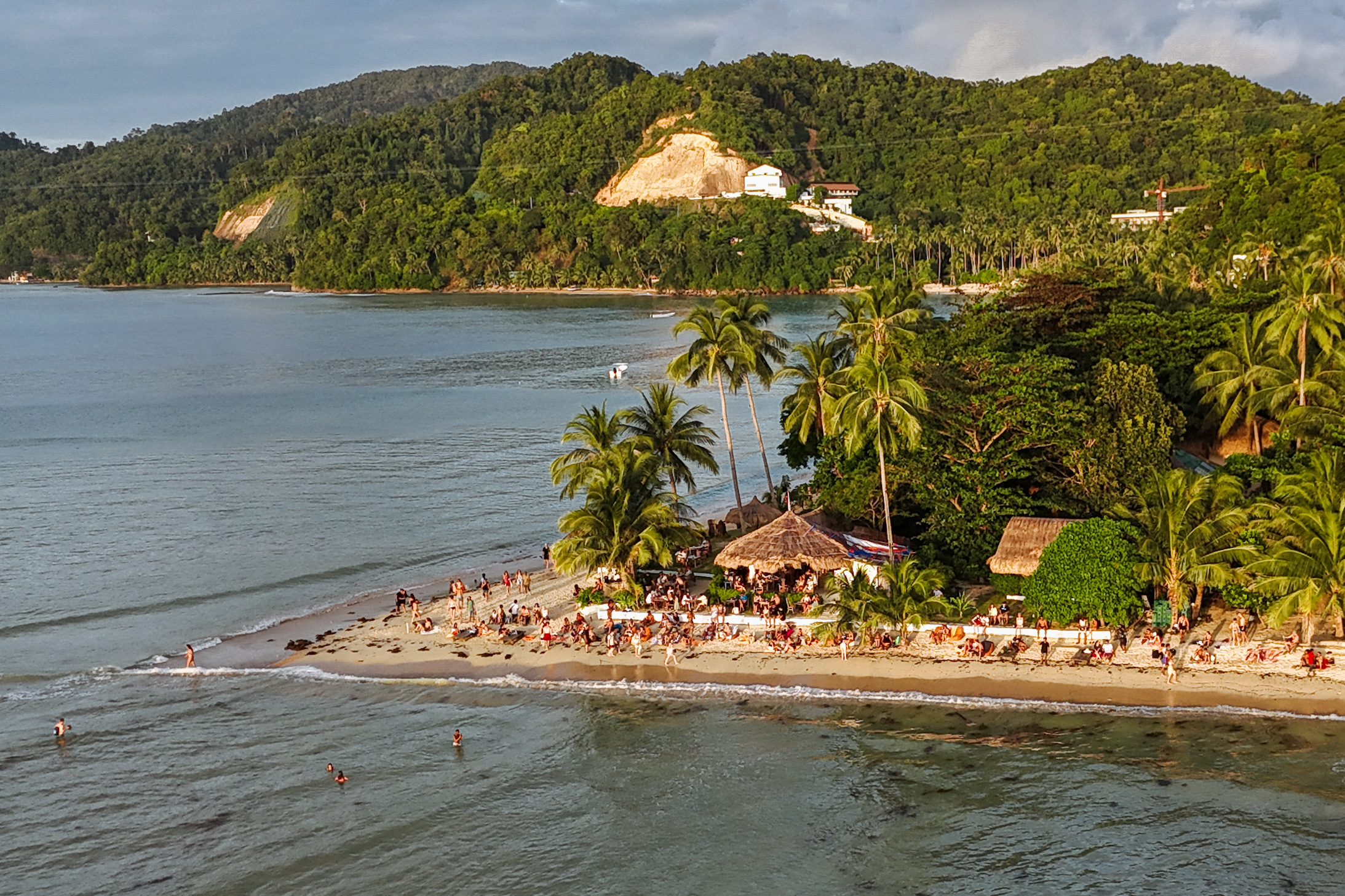 Drone shot of a beach during golden hour with people watching the sunset