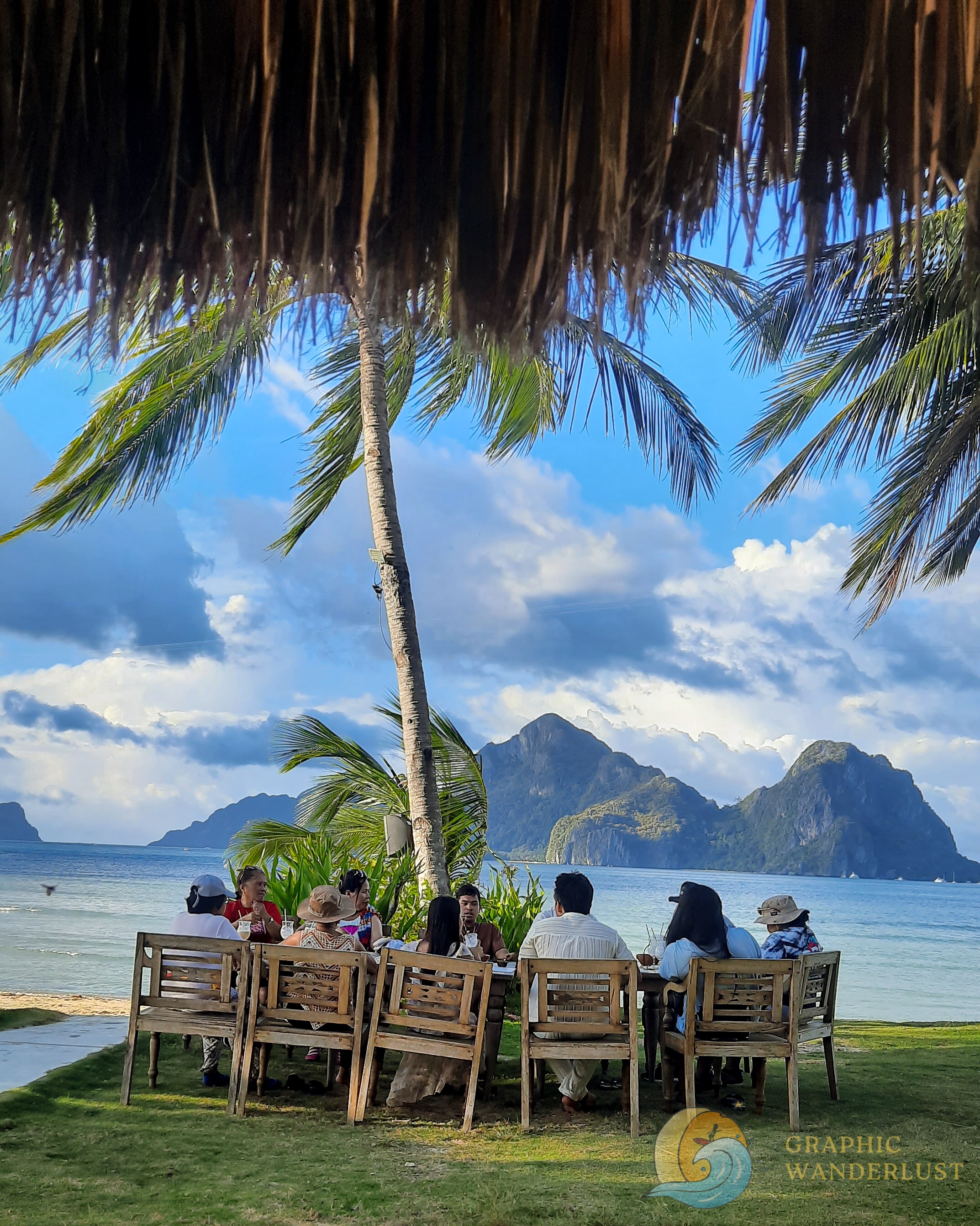 People dining with a background of limestone cliffs and the beach