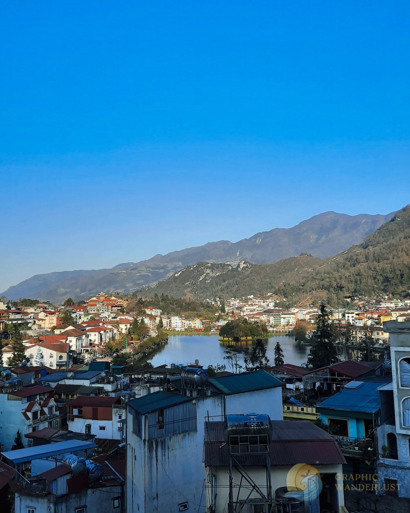 Scenic view of a mountainous town with a manmade lake at the center and mountain range surrounding it