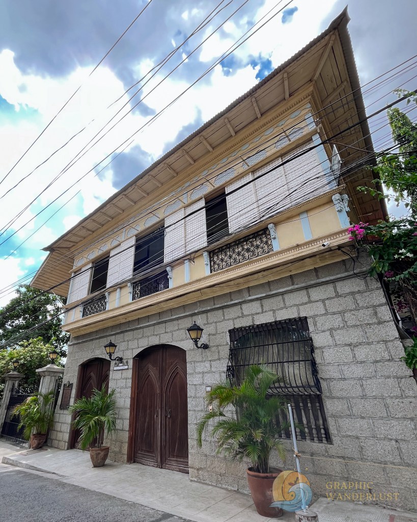 Facade of a Spanish colonial house in Taal, Batangas, featuring a mix of light blue and yellow hues, with intricate details and wooden doors.