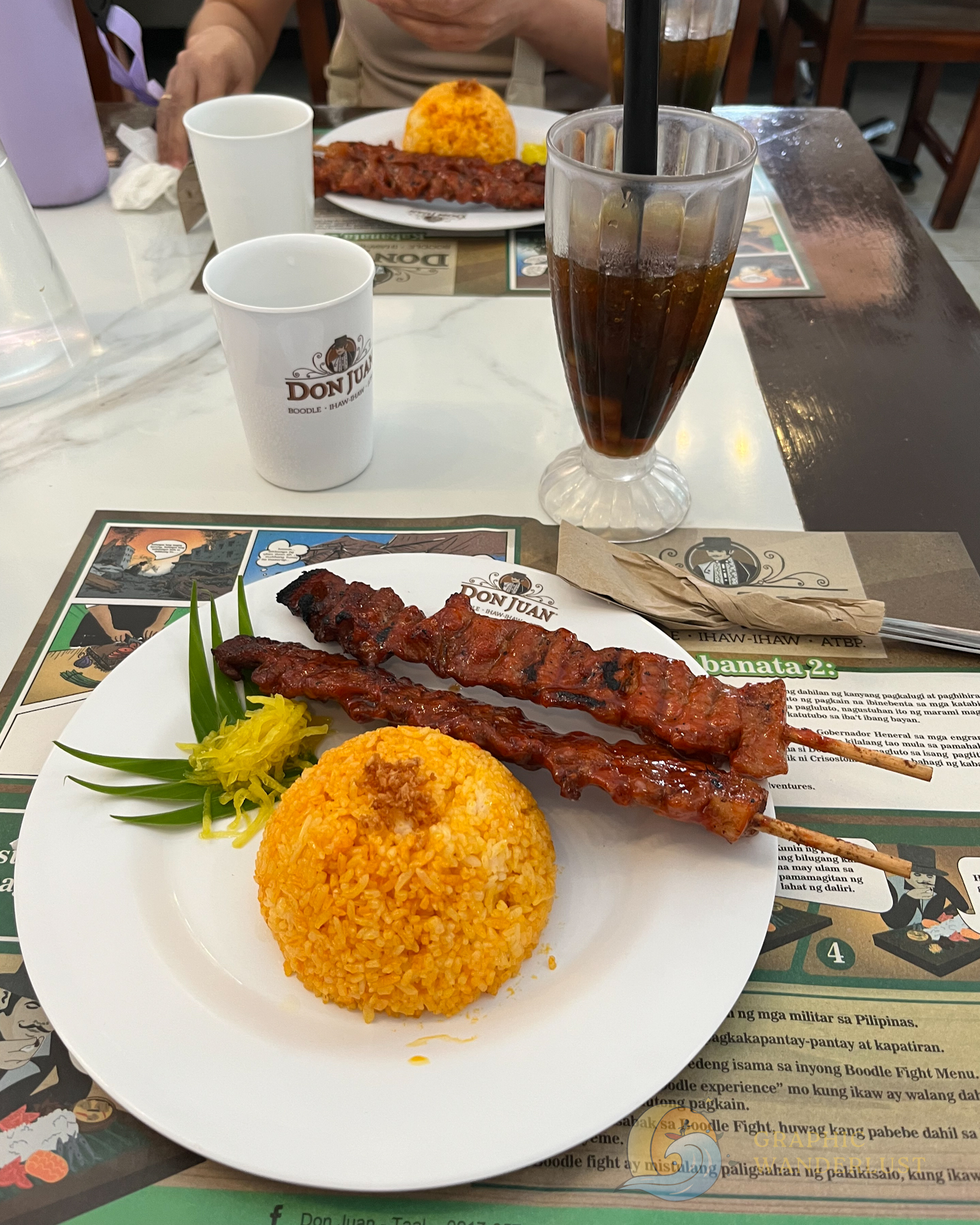 A serving of pork barbecue and rice with a glass of beverage in the foreground.