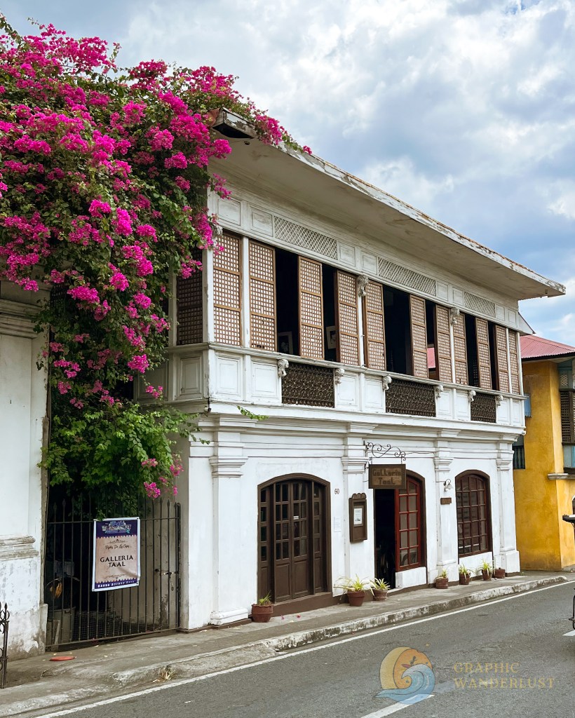 Facade of the Galleria Taal, a Spanish colonial house in Taal, Batangas, adorned with vibrant bougainvillea flowers and featuring traditional architectural details.