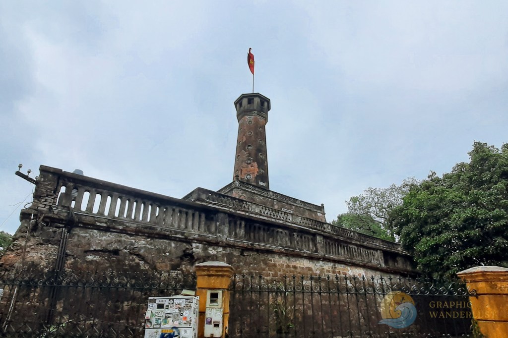 The Imperial Citadel of Thang Long in Hanoi, Vietnam, featuring a historic watchtower and surrounding walls under a cloudy sky.