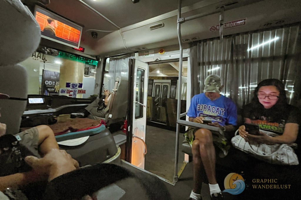 Interior of a bus with passengers seated and viewing screens, highlighting the comfortable travel experience.