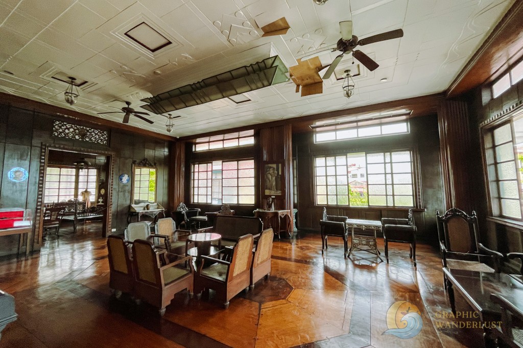 Interior of a historical Spanish colonial house in Taal, Batangas, featuring wooden floors, vintage furniture, and large windows allowing natural light.