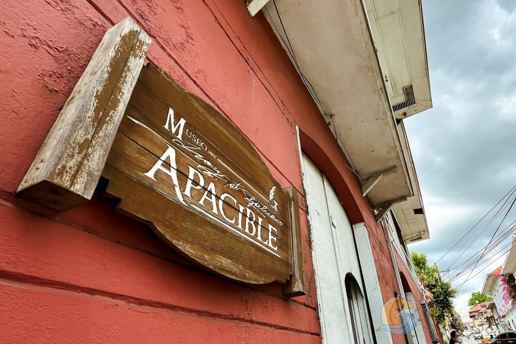 Signage of Museo Nina Leon at Galicano Apacible, featuring wooden design and lettering, set against a red wall.