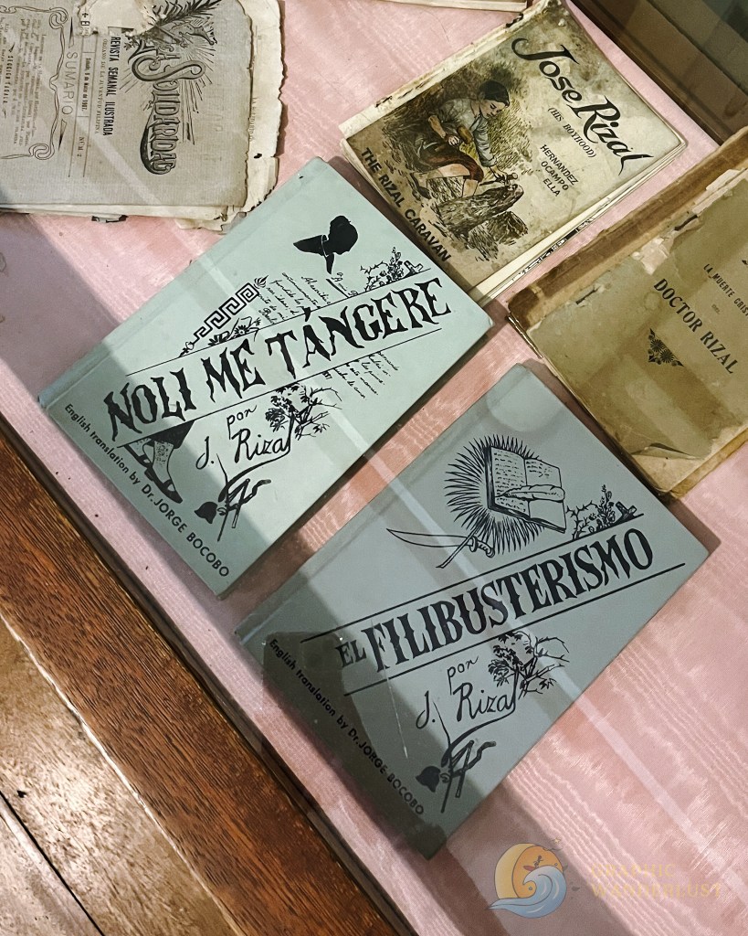 Close-up view of two books, "Noli Me Tangere" and "El Filibusterismo" by José Rizal, displayed in a glass case with other historical texts.