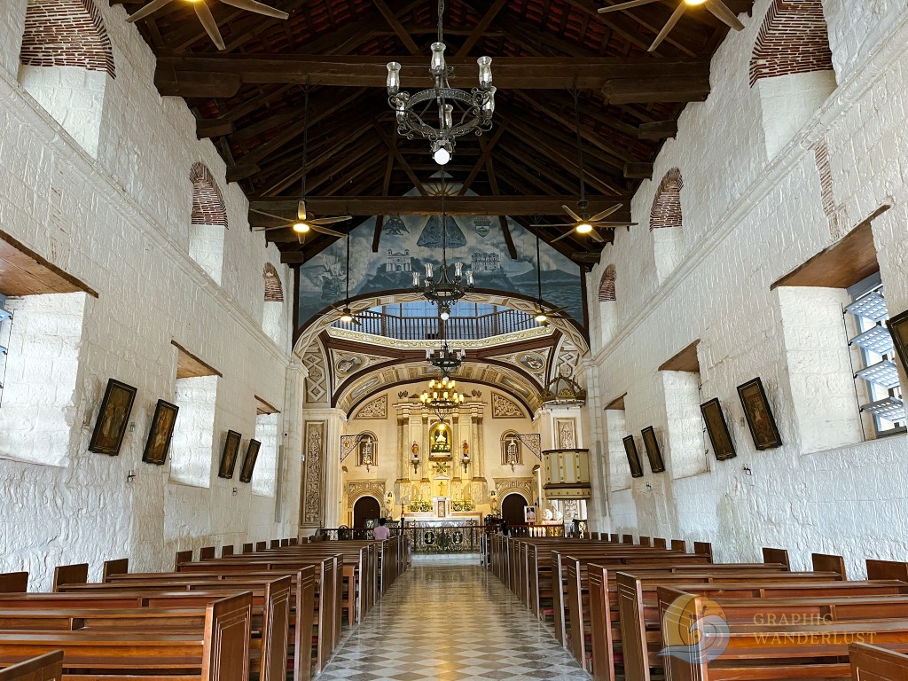 Interior of Taal Basilica showcasing its ornate altar, wooden pews, and high ceiling with intricate details.