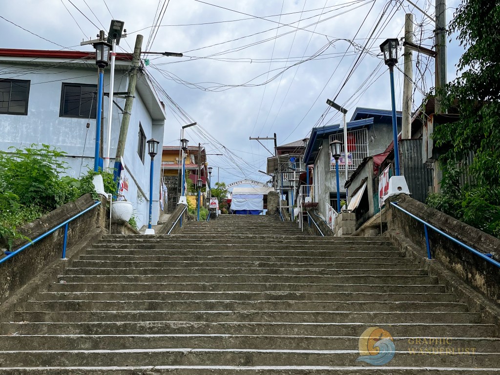 Staircase leading to the heritage town of Taal, Batangas, flanked by residential buildings and street lamps.