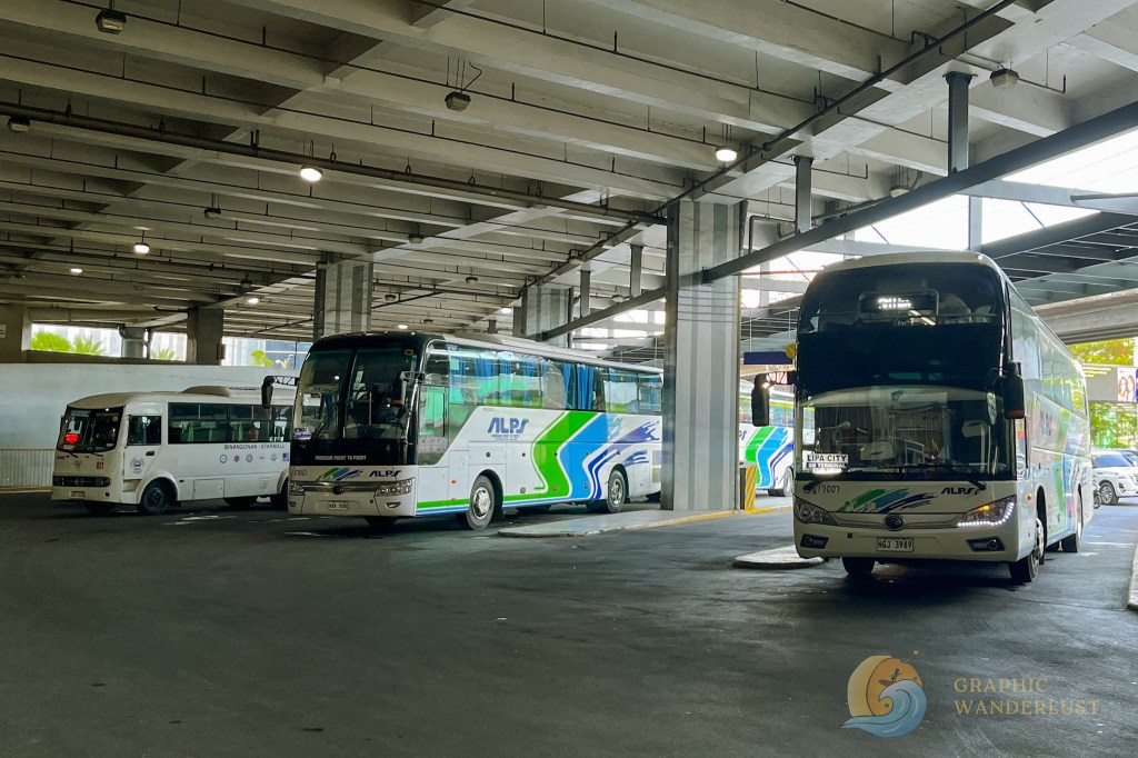 Bus terminal in the Philippines featuring various buses, including ALPS buses, parked under a covered structure.