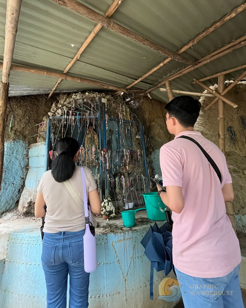 Visitors at the Sta. Lucia Well in Taal, Batangas, observing the area with colorful offerings and pots.