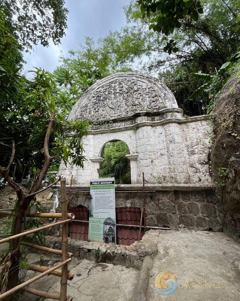 Entrance to the Sta. Lucia Well, a sacred site in Taal, Batangas, featuring intricate stonework and surrounded by greenery.