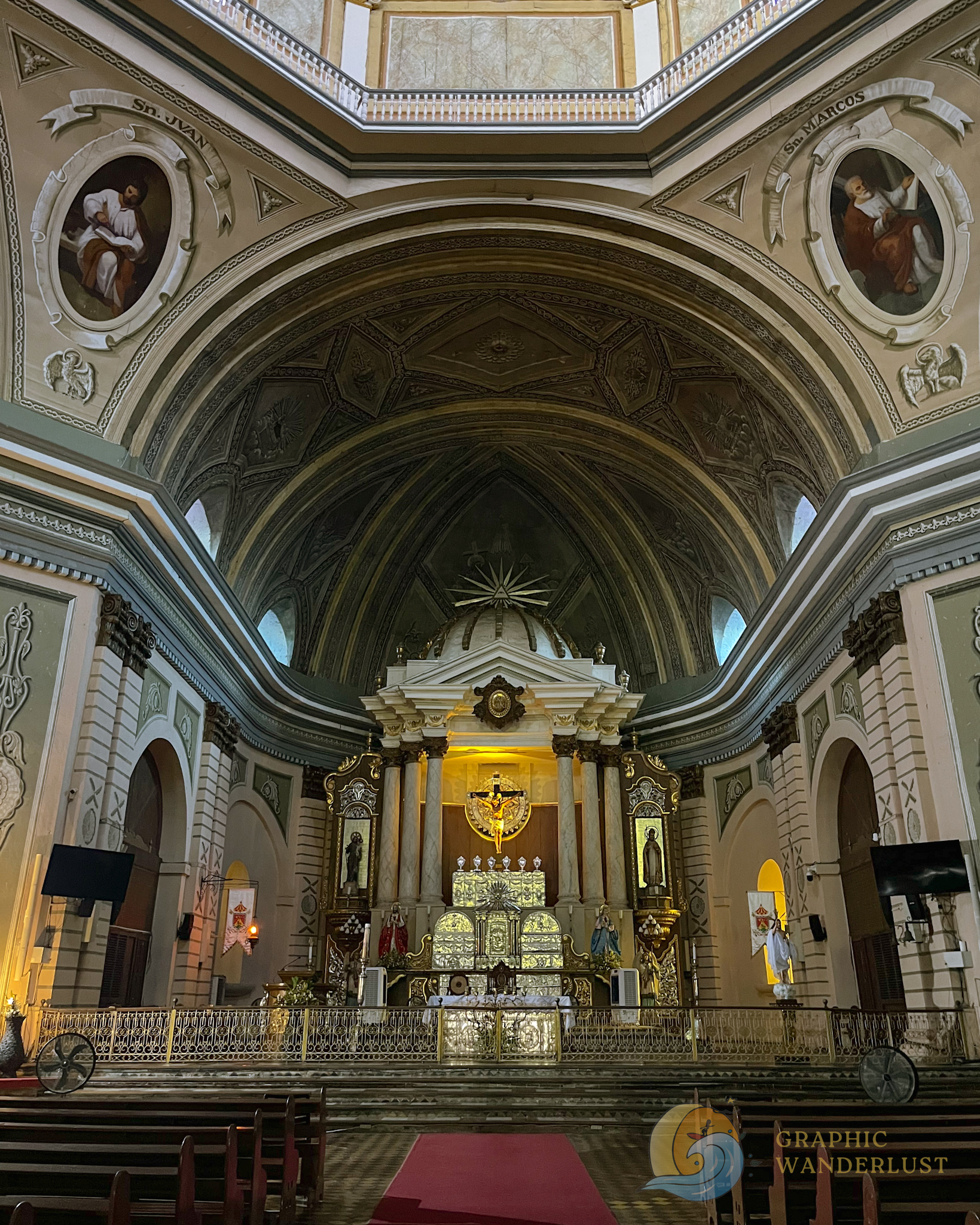 The main altar of a church in Taal, Batangas highlighted by its trompe l'oeil ceilings and neoclassical columns framing the image.