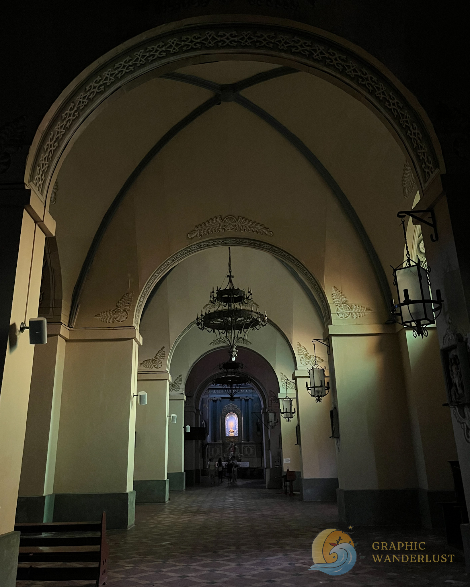 Side aisle of Taal Basilica in Taal, Batangas featuring a vaulted ceiling and with an image displayed at the end of it.