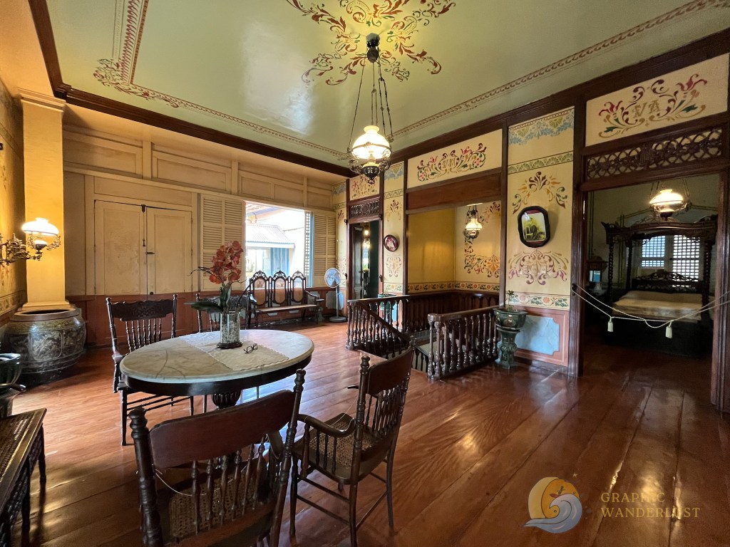 Interior of a Spanish colonial house in Taal, Batangas, featuring ornate hand-painted ceilings, wooden furniture, and traditional decor.