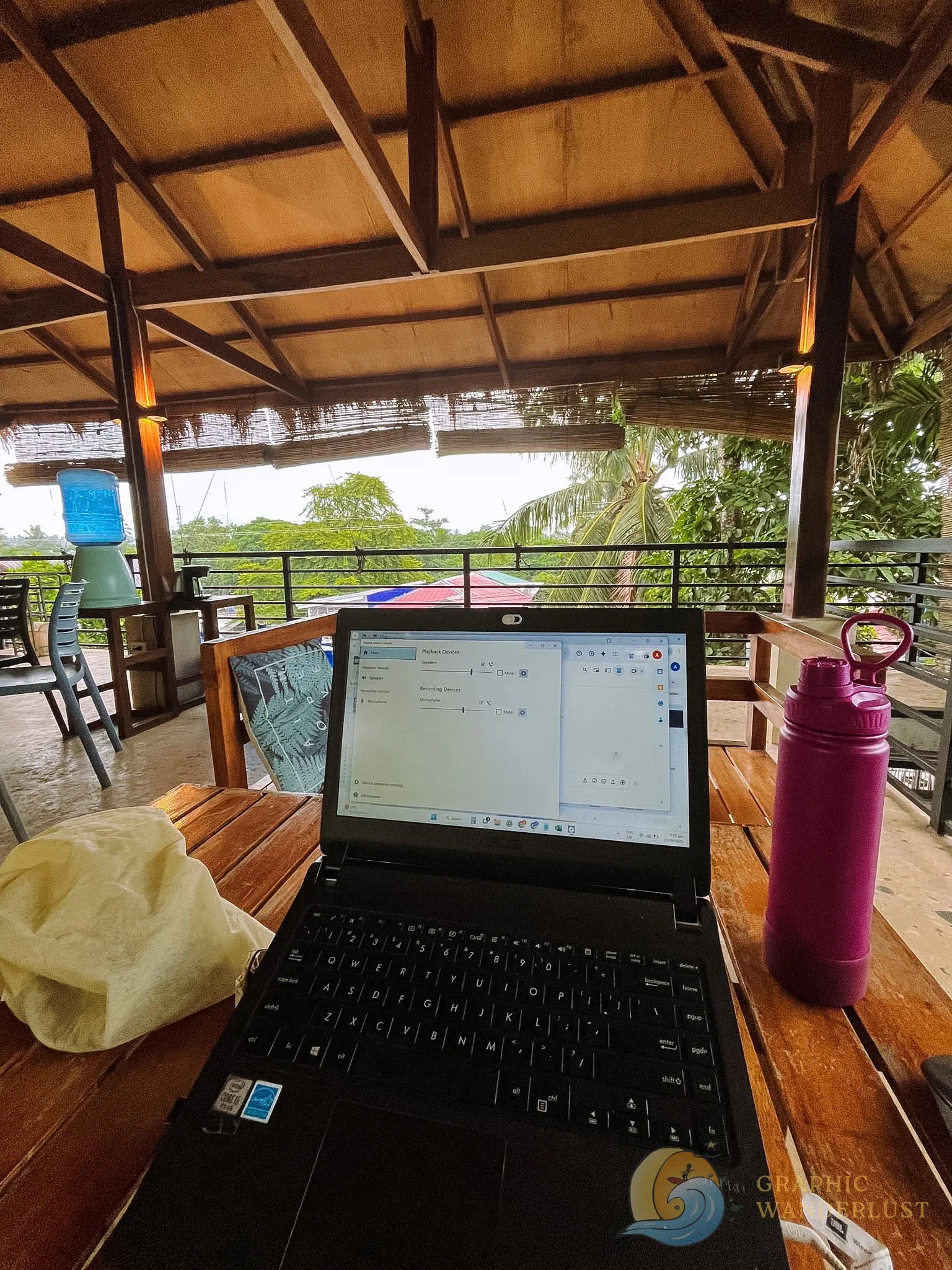 POV of a remote worker in Siargao facing her laptop with a view of lush tropical greenery in the background