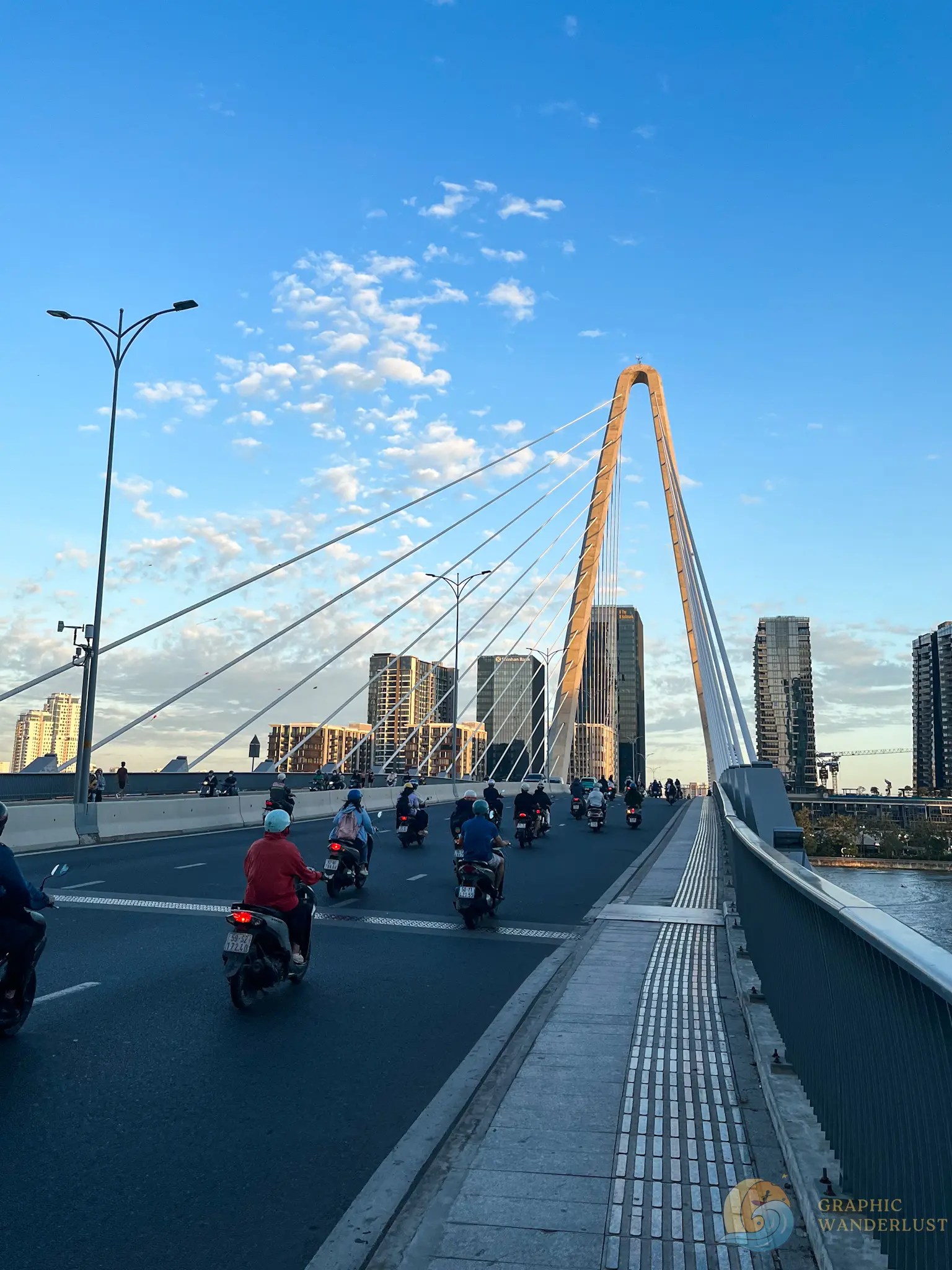 Bikers driving throuh a cable-stayed bridge during a clear afternoon.