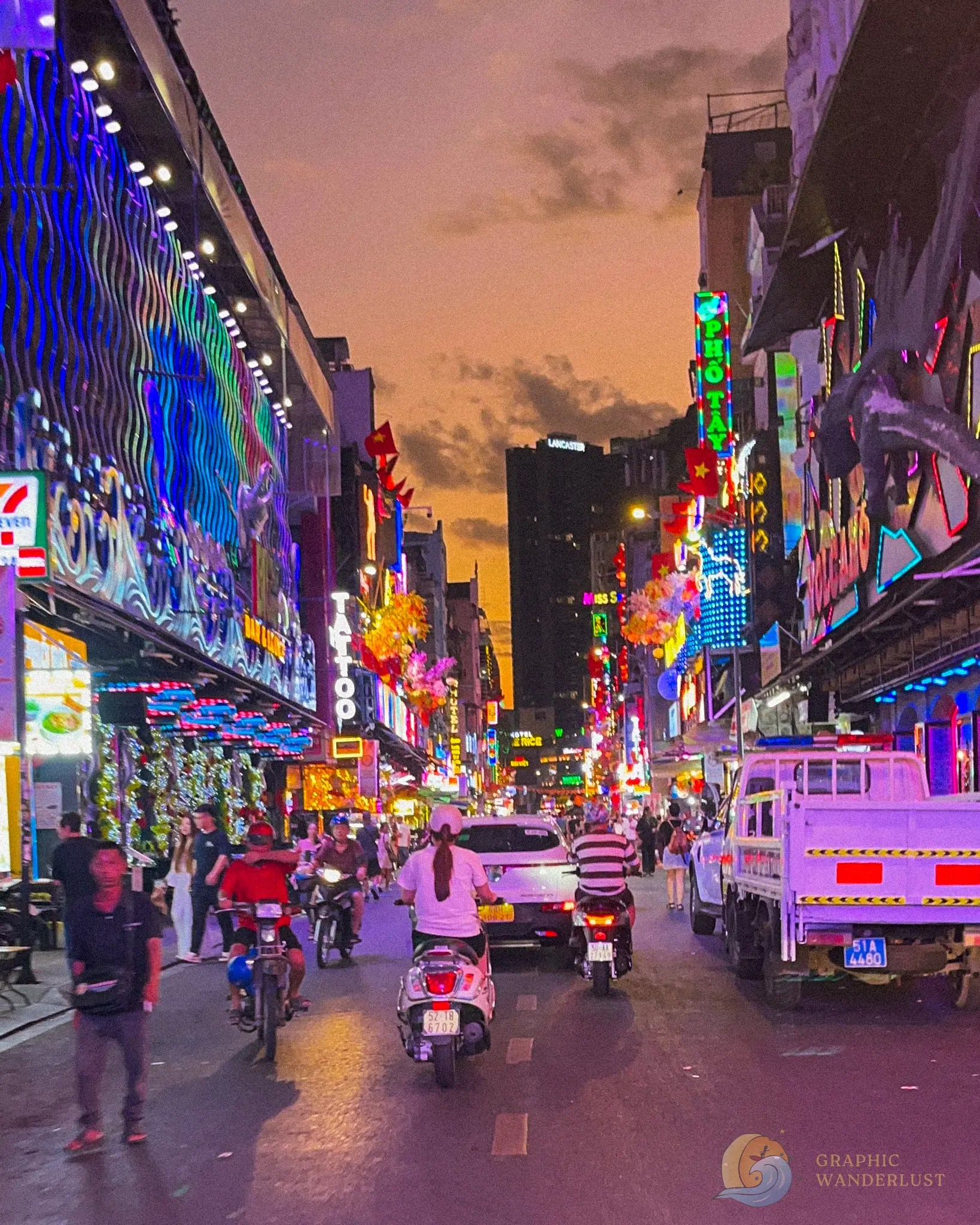 A busy street scene illuminated by colorful neon lights at dusk, featuring pedestrians and motorbikes navigating through the lively atmosphere.