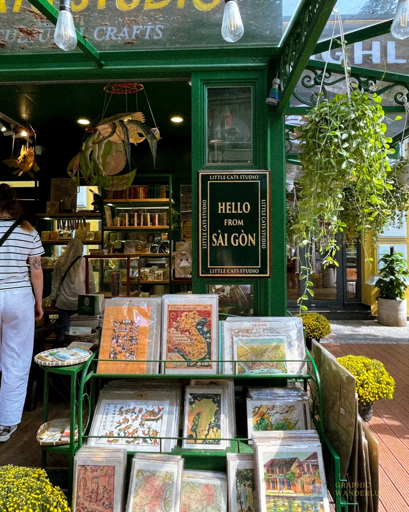 A storefront with a display of vintage colonial Saigon posters and a 'Hello Saigon' marker.