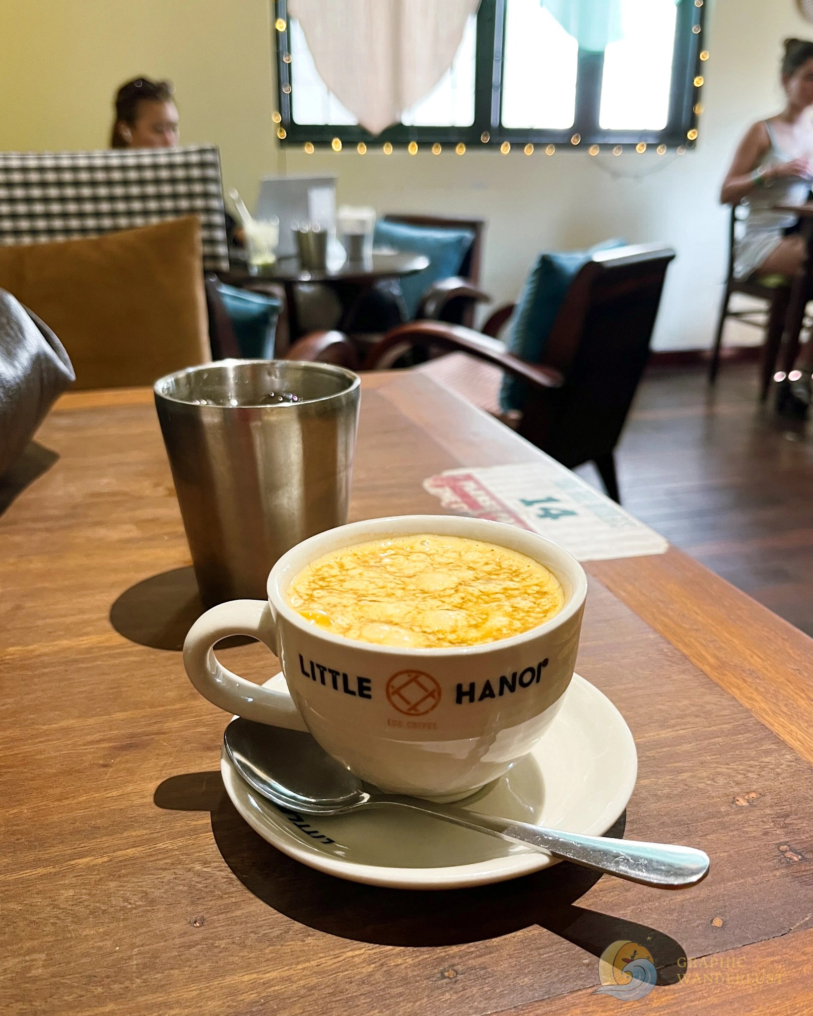 A serving of a cup of coffee with a background of tables and chairs.