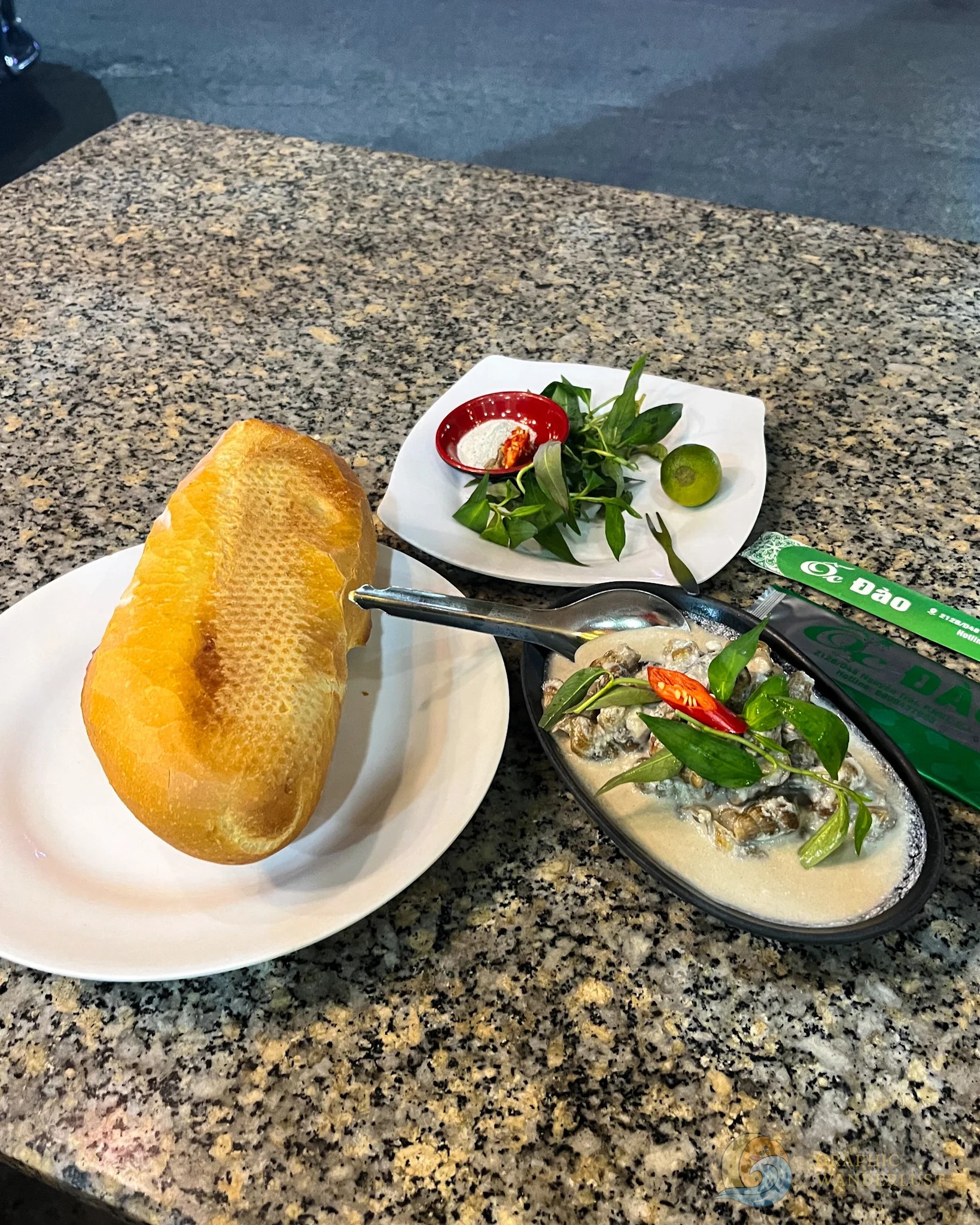 A serving of snails in coconut milk, baguette and condiments on a table. 