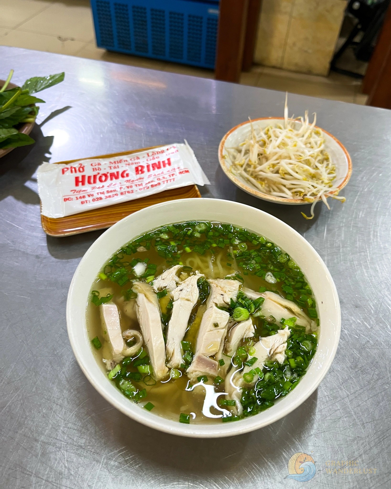 A serving of chicken noodle soup with bean sprouts in the background.