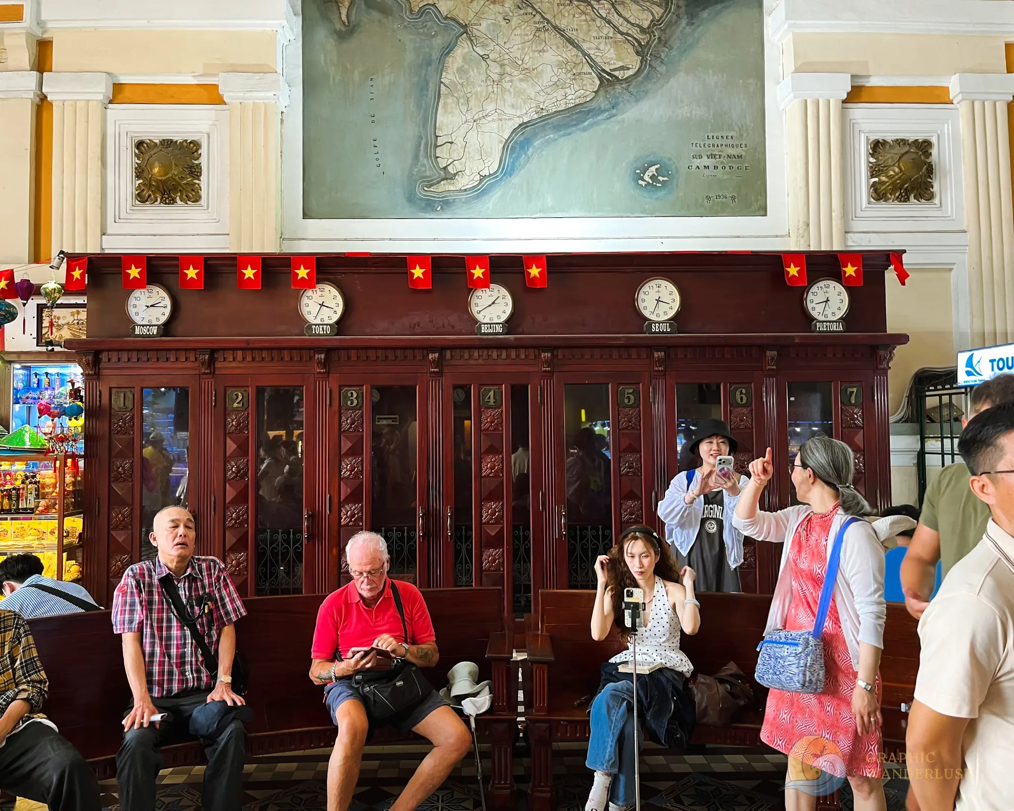 Tourists sitting infront of the wooden telephone booths found in Saigon Central Post Office.