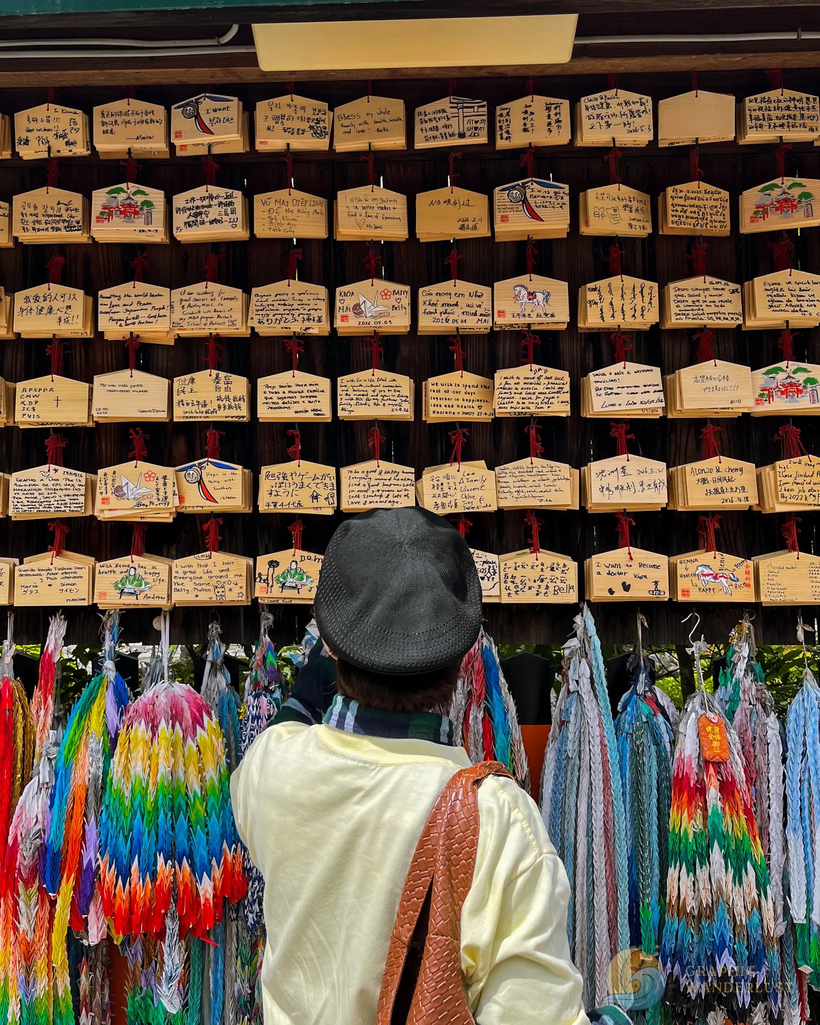A man infront of wooden wishing tablets at Fushimi Inari Taisha.