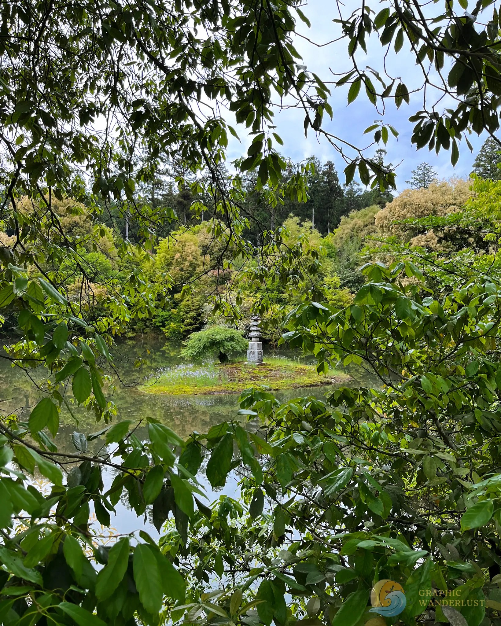 A stone structure in the middle of an island standing in the middle of a pond surrounded by lush greenery.