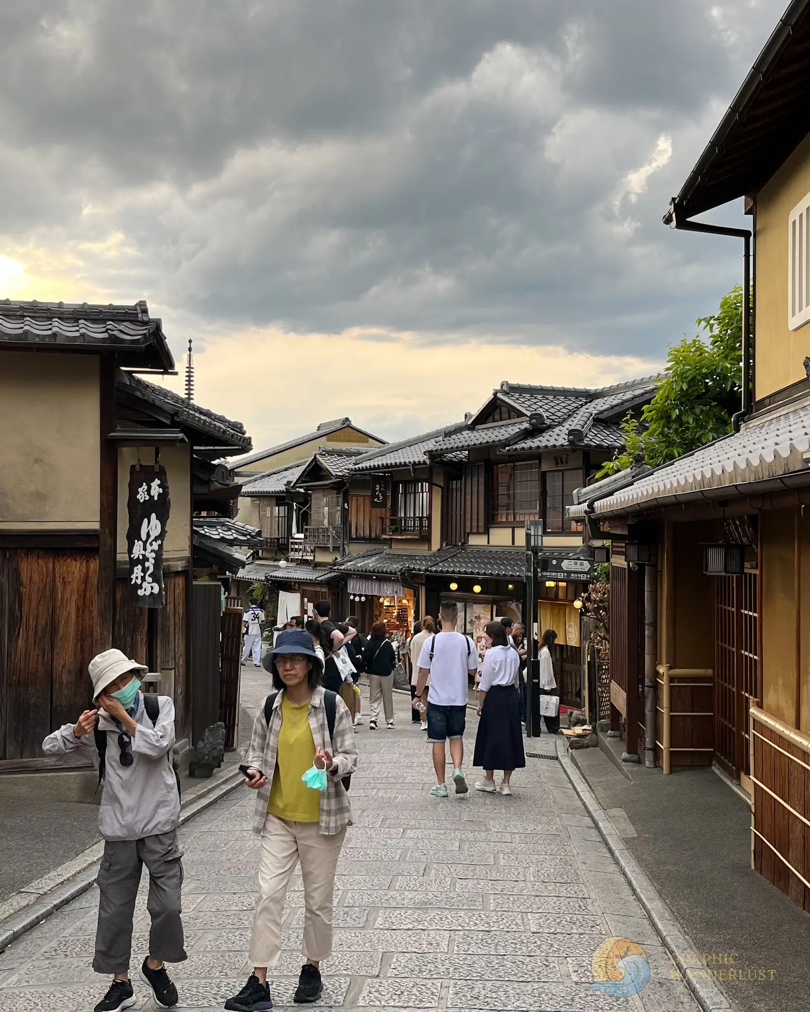 Rows of machiya with a small number of tourists walking along its cobblestone street.