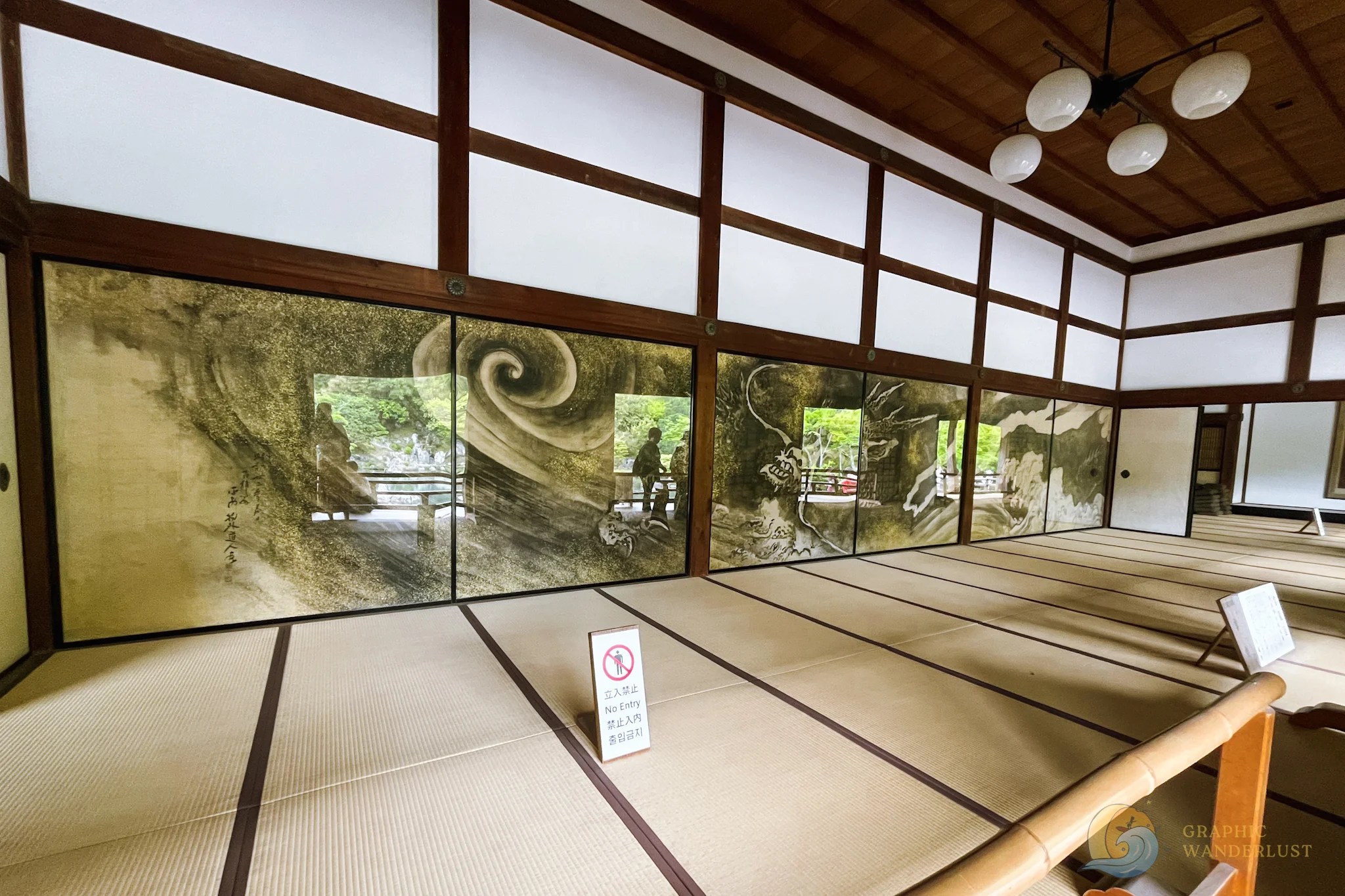 An interior of a traditional Japanese building with tatami mats and wall artwork that runs across the entire building.