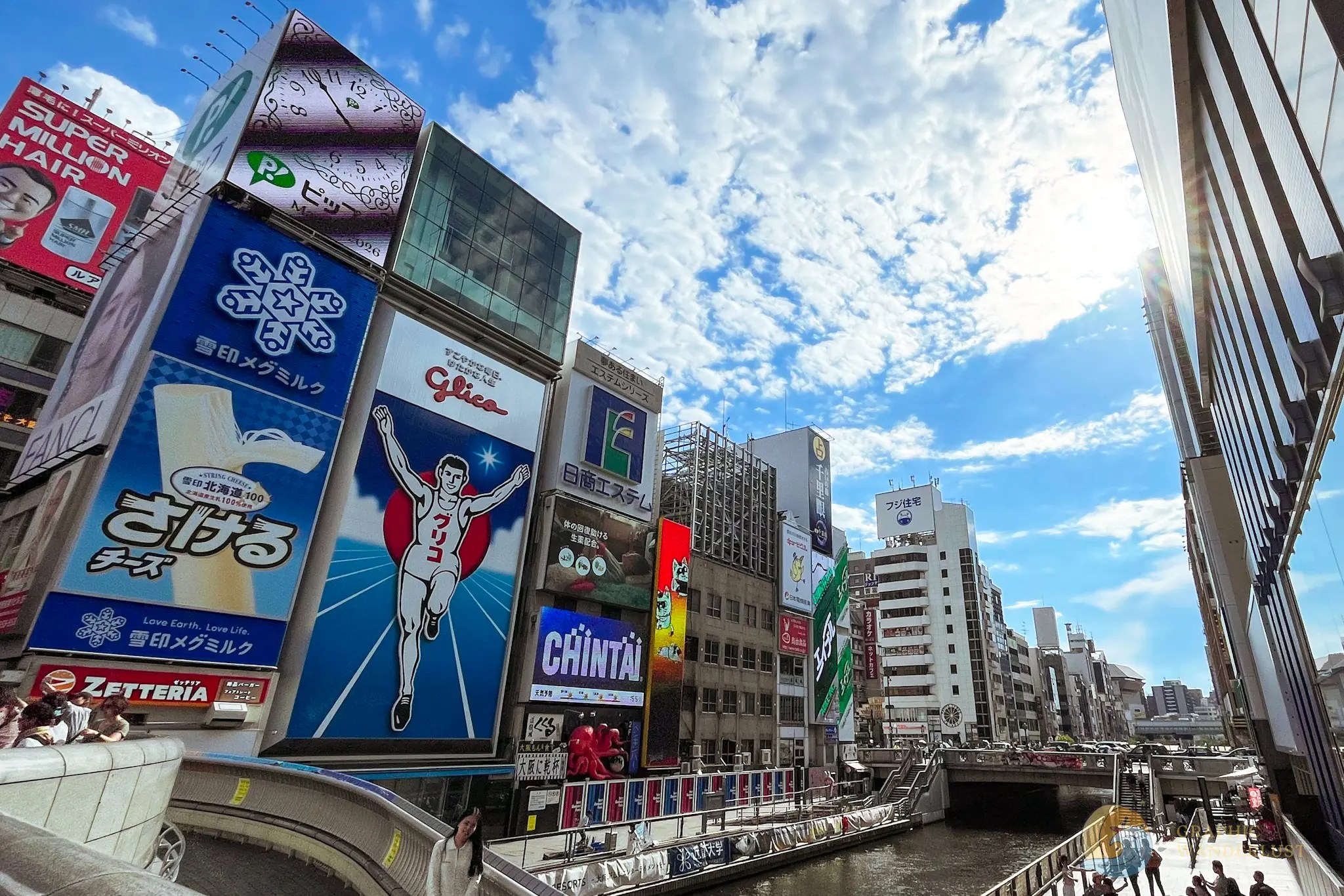 Dotonbori Billboards and advertisements along a canal in an urban area under a partly cloudy sky