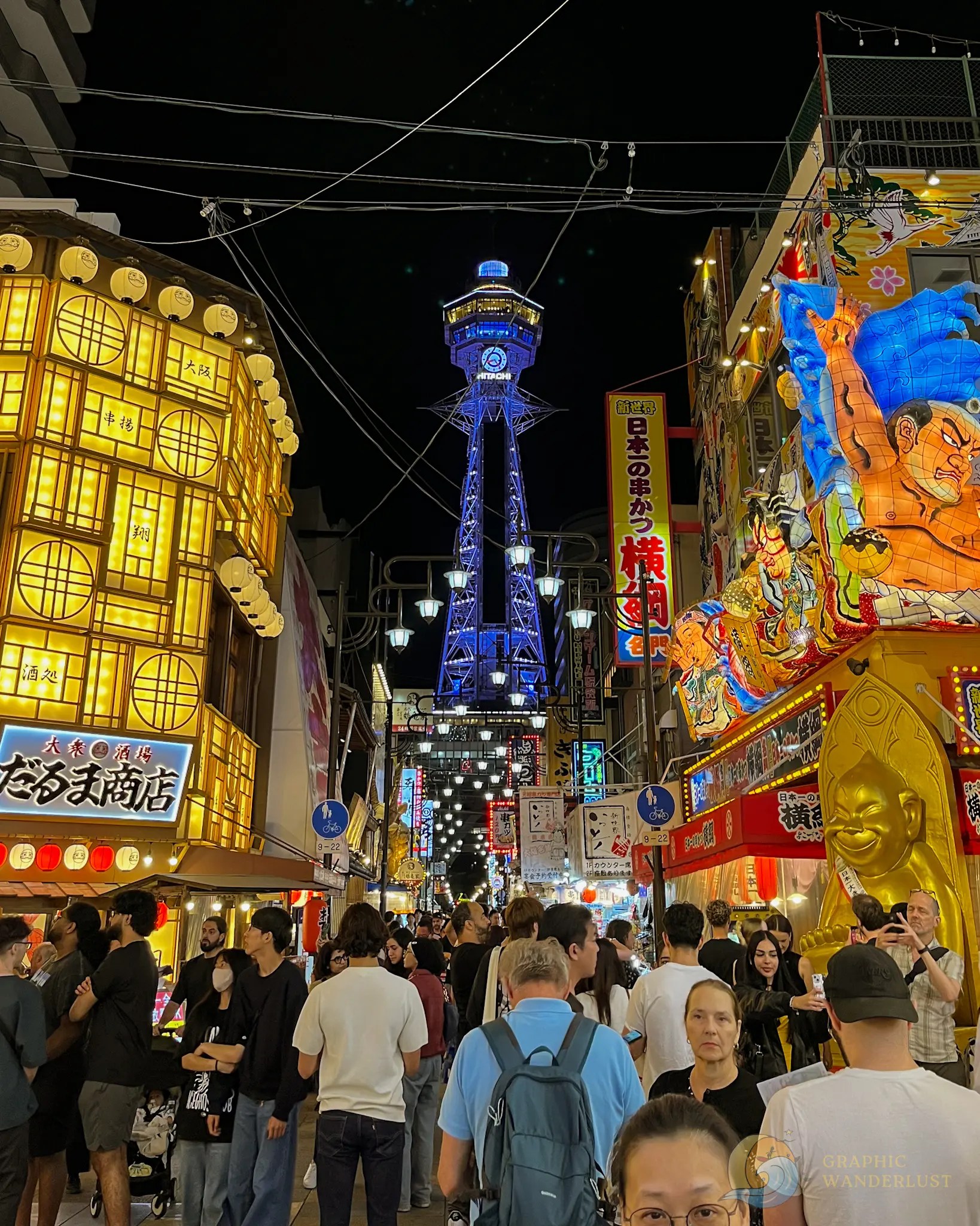 Shinsekai Crowded street at night with illuminated signs and Tsutenkaku Tower in Osaka, Japan