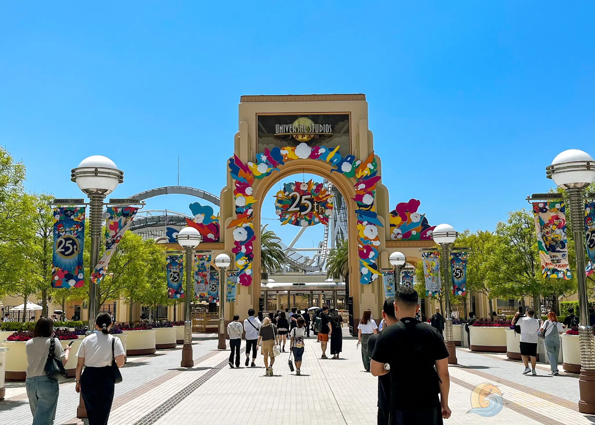 Universal Studios Japan Entrance arch of Universal Studios Japan decorated for the 25th anniversary with colorful flowers and banners, and people walking towards it