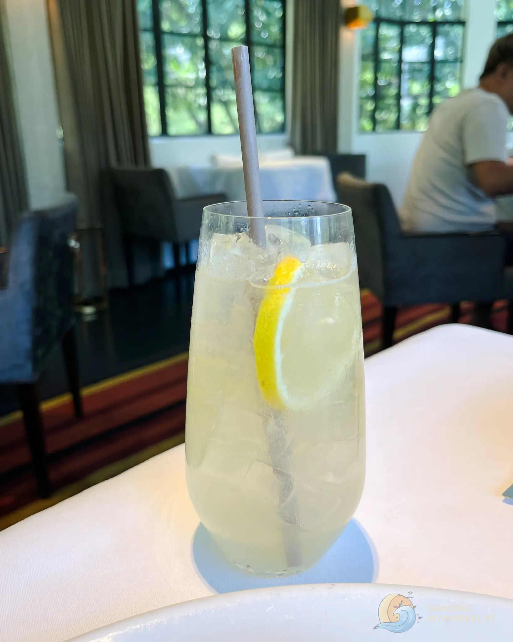 Glass of iced lemon drink with a straw on a restaurant table