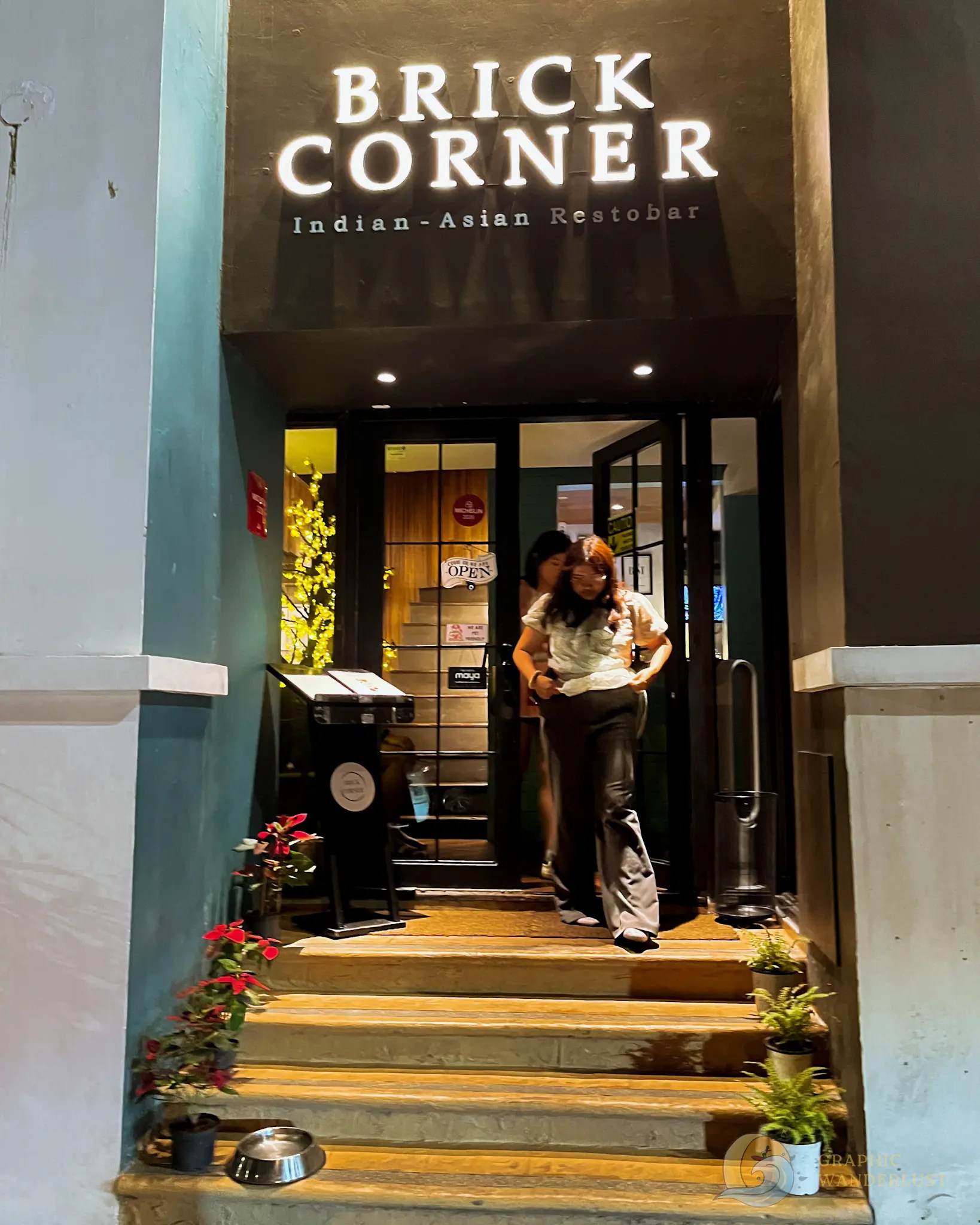 Brick Corner Indian-Asian Restobar entrance with two people standing on the steps
