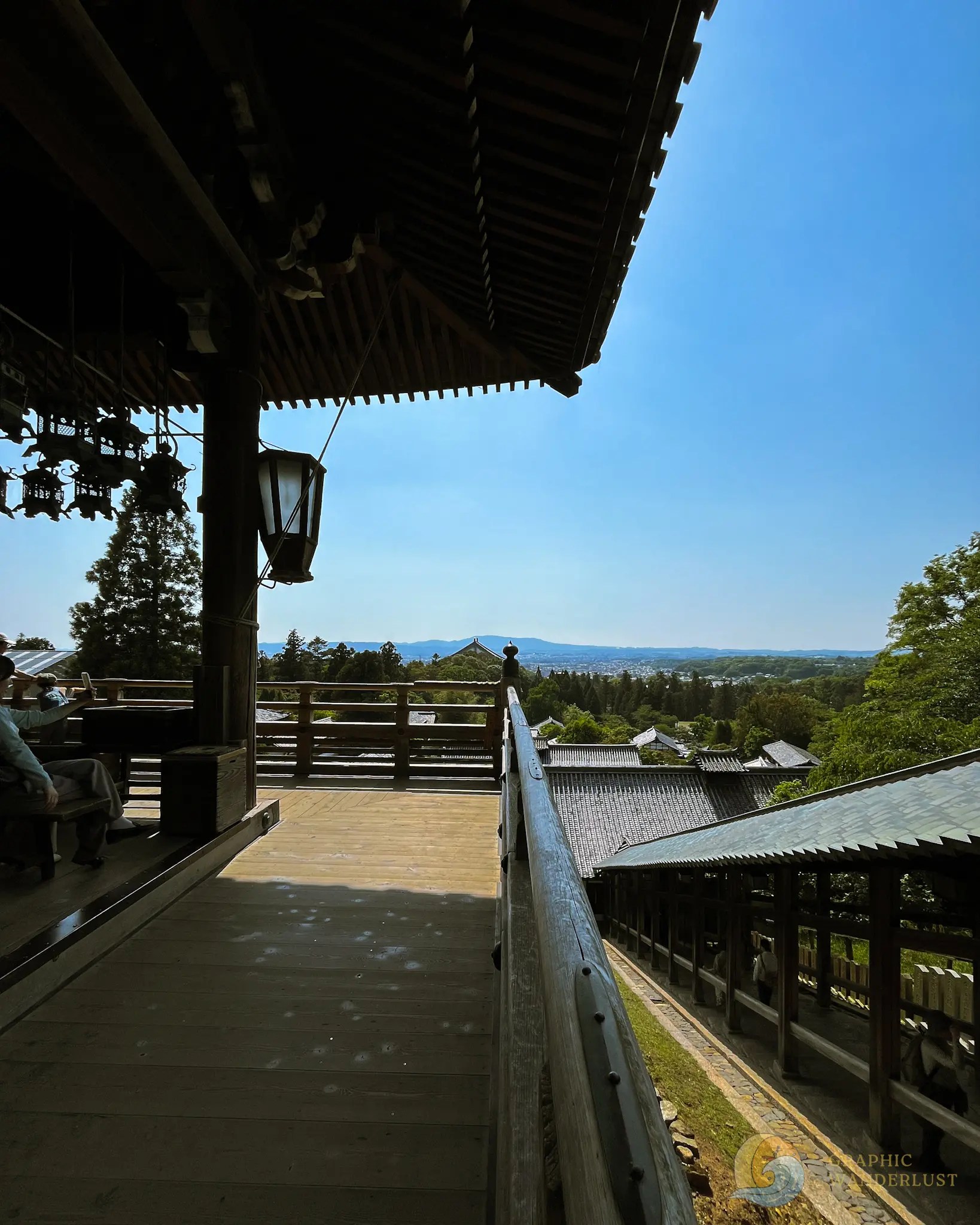 A balcony overlooking a landscape with a clear sky and mountain in the horizon.