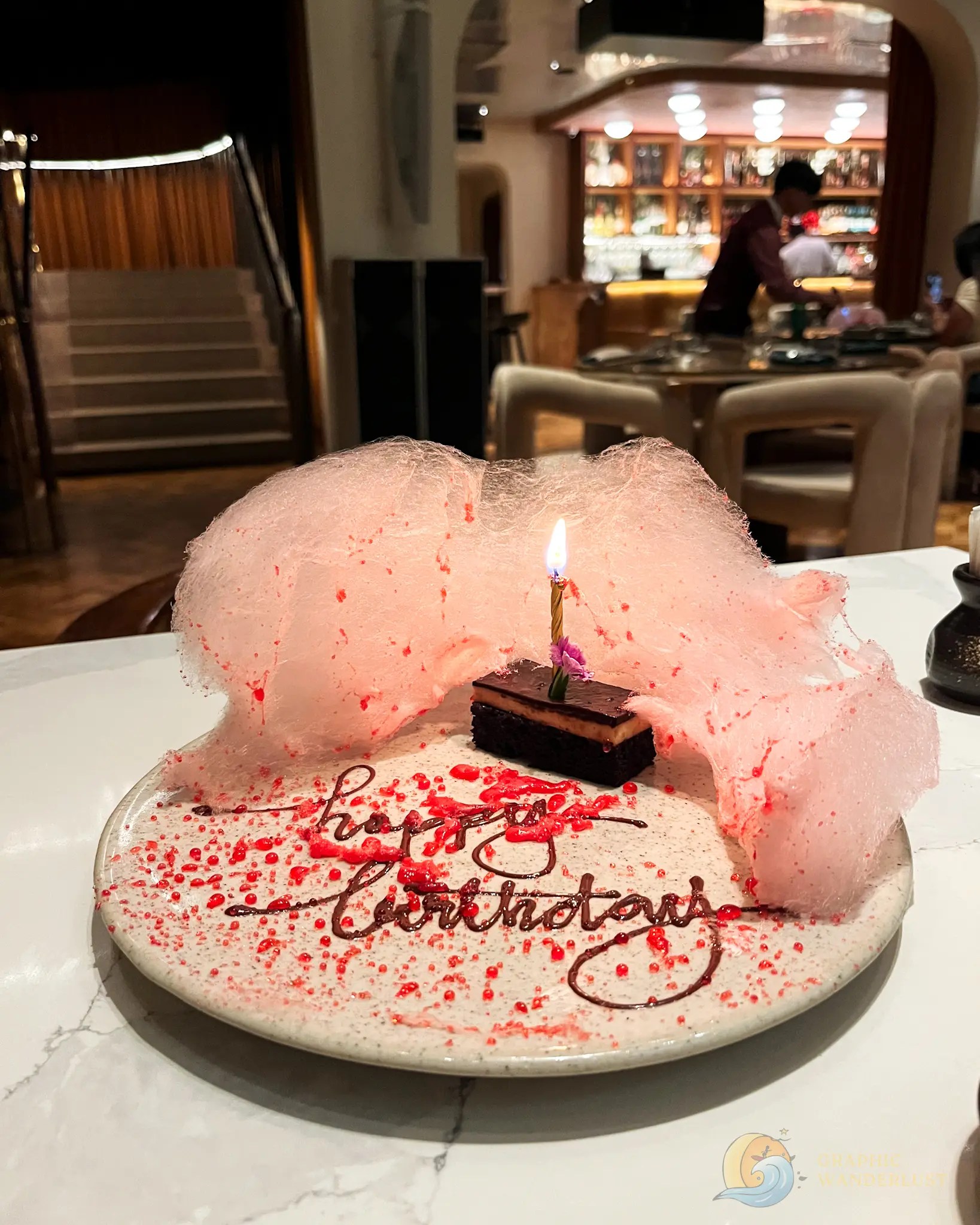 Uma Nota Manila Birthday Cake Slice Pink cotton candy dessert with a lit candle and chocolate birthday message in a restaurant