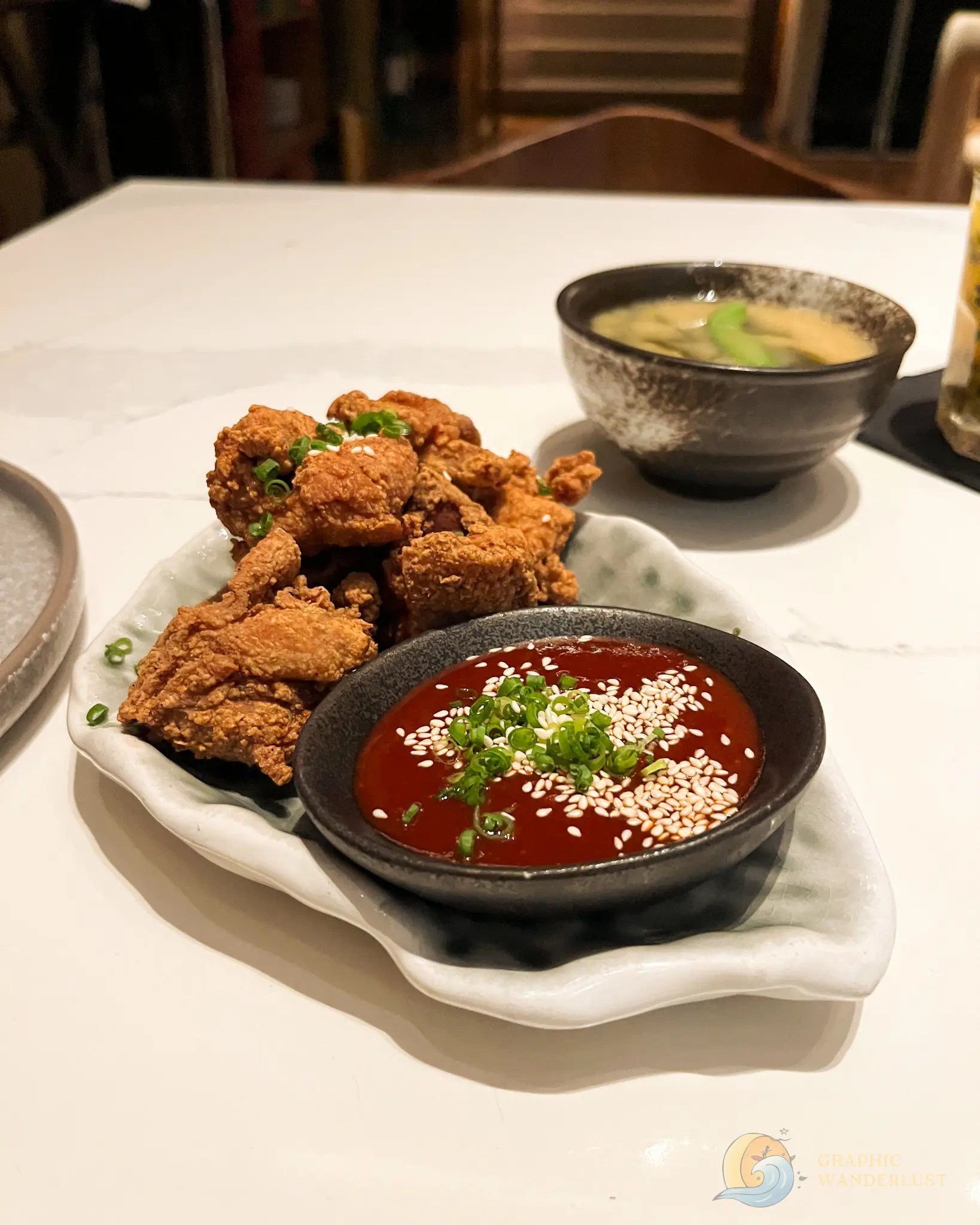 Crispy fried chicken with red dipping sauce and soup on a restaurant table