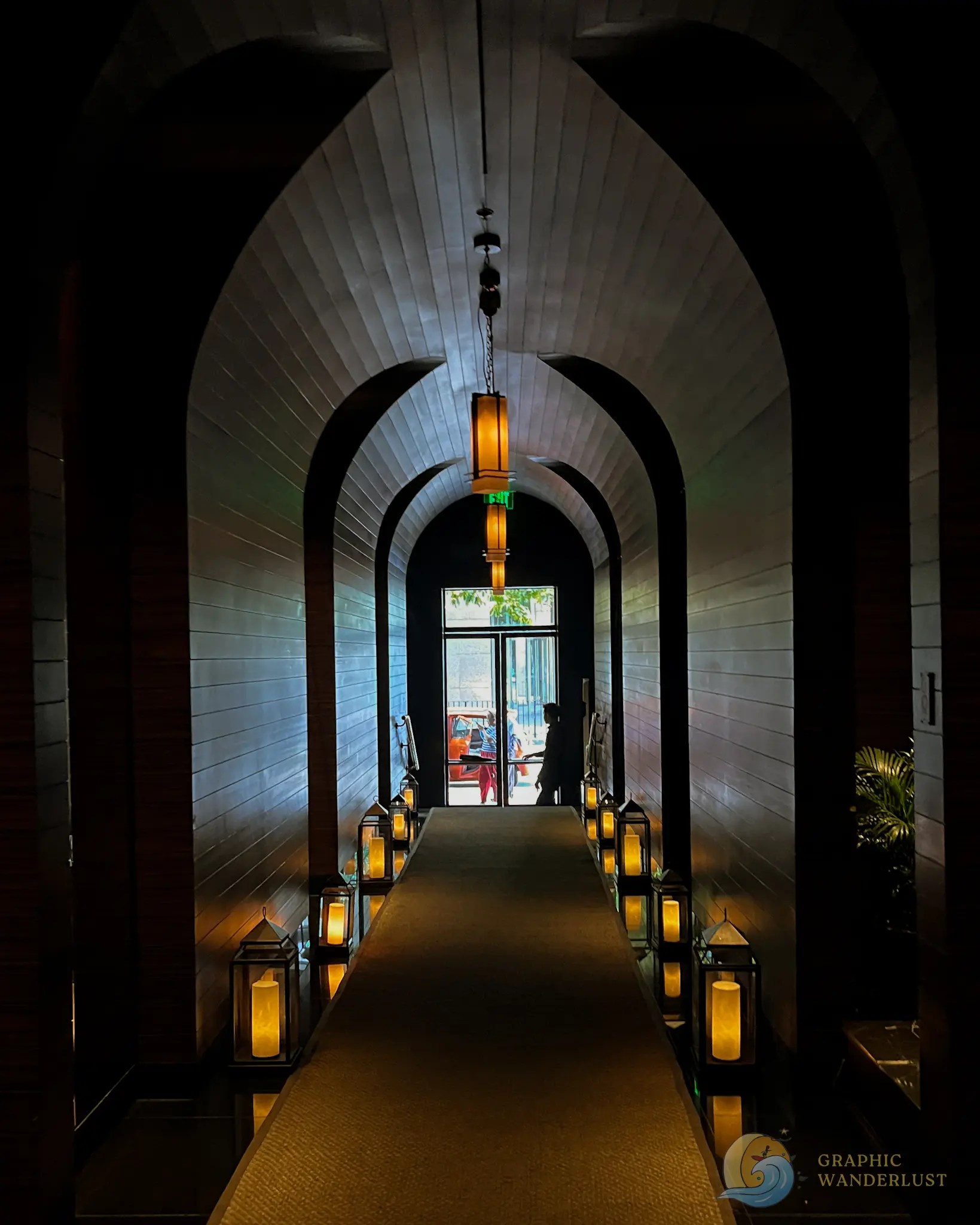 Dimly lit arched hallway lined with glowing lanterns and hanging lights